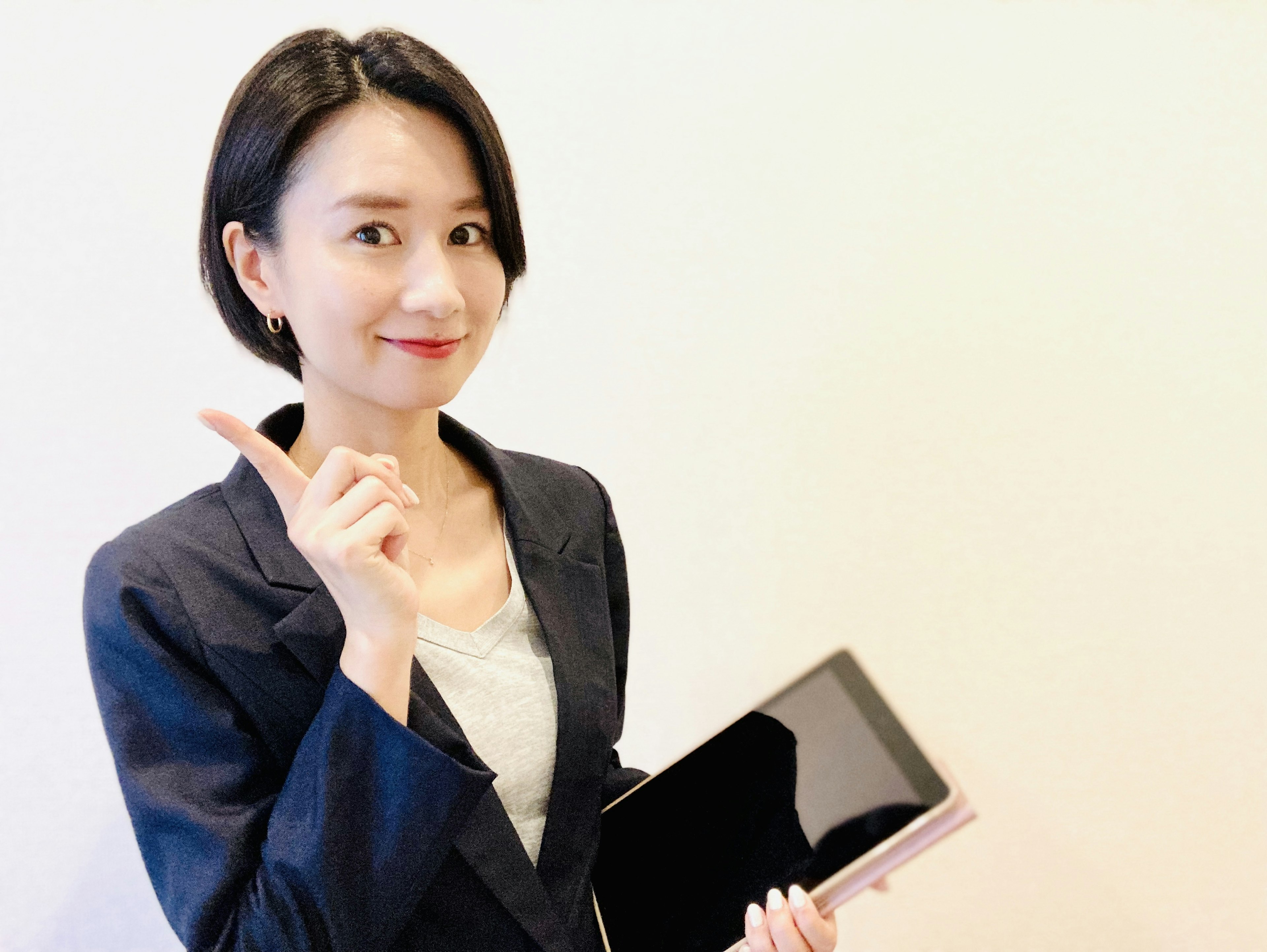 Woman in business suit holding a black tablet and pointing with her finger