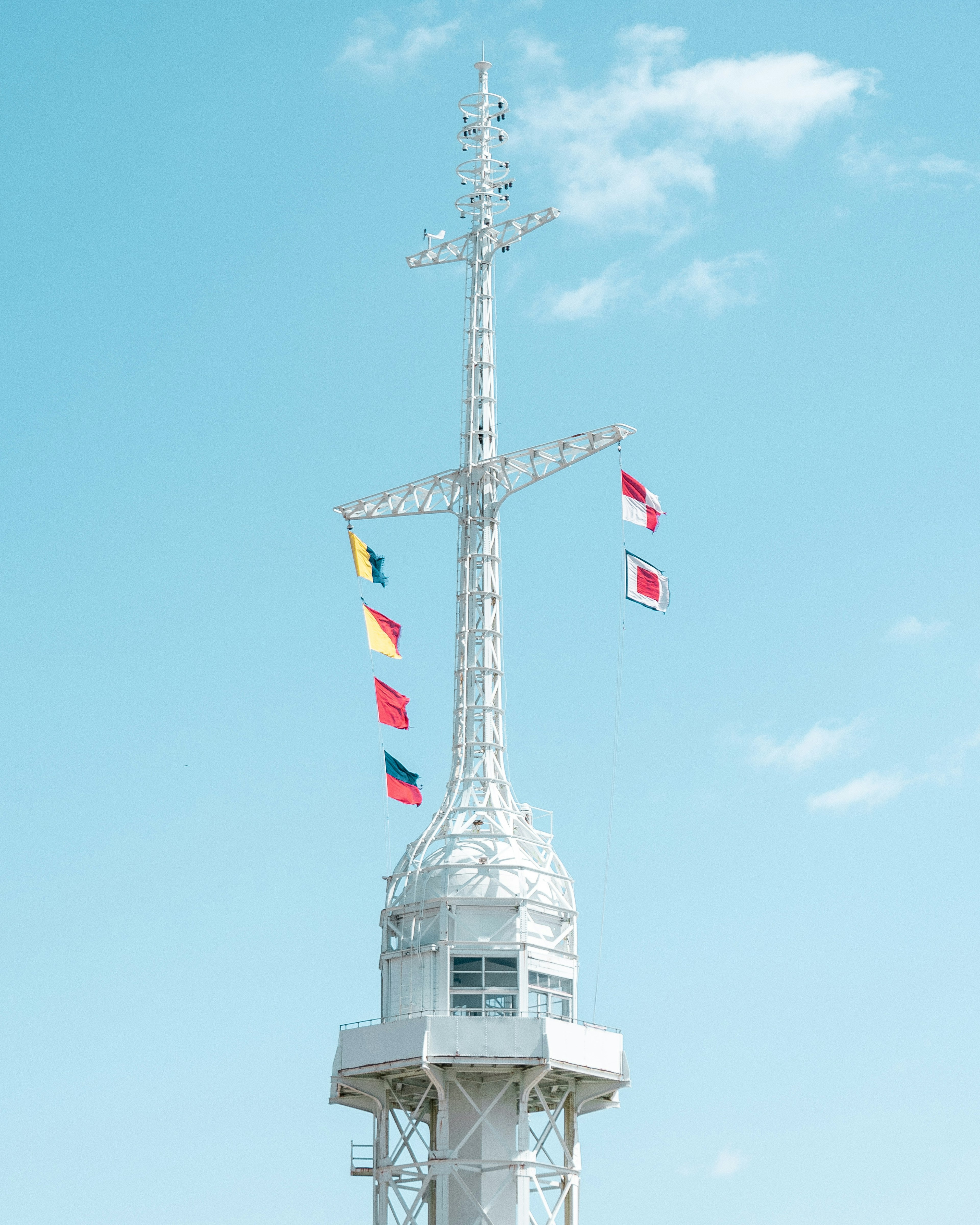 White communication tower with flags waving against a blue sky