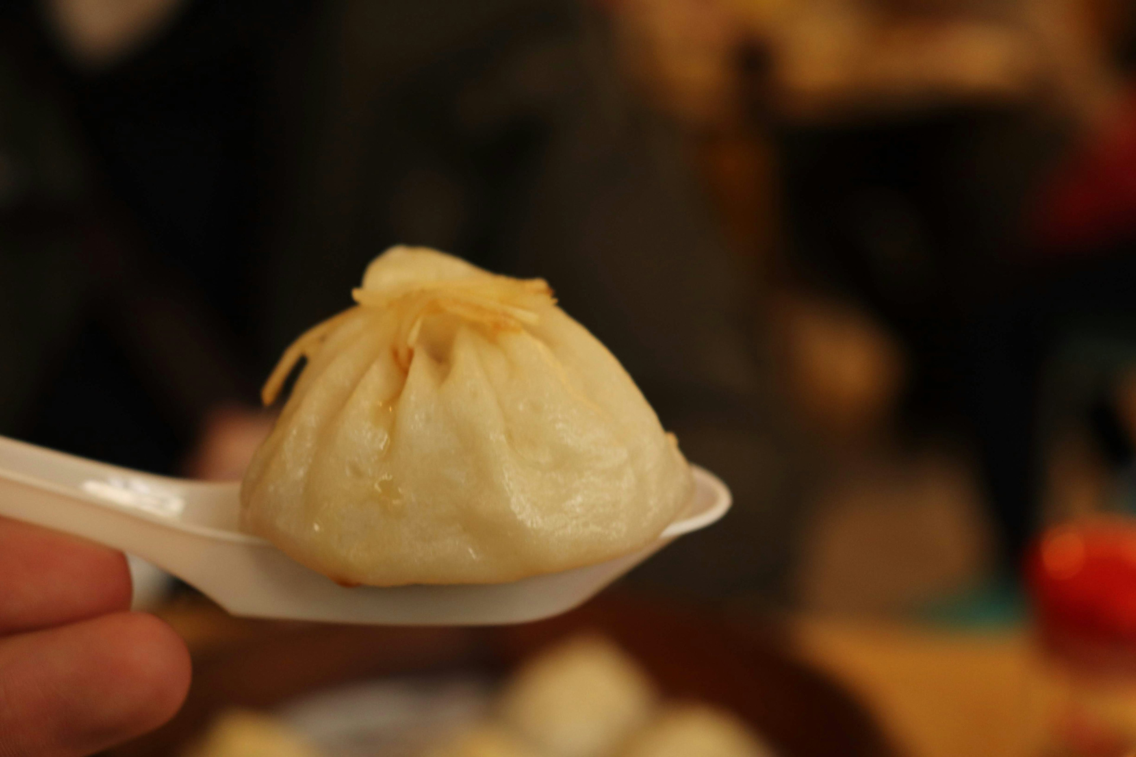 A xiaolongbao held above a spoon