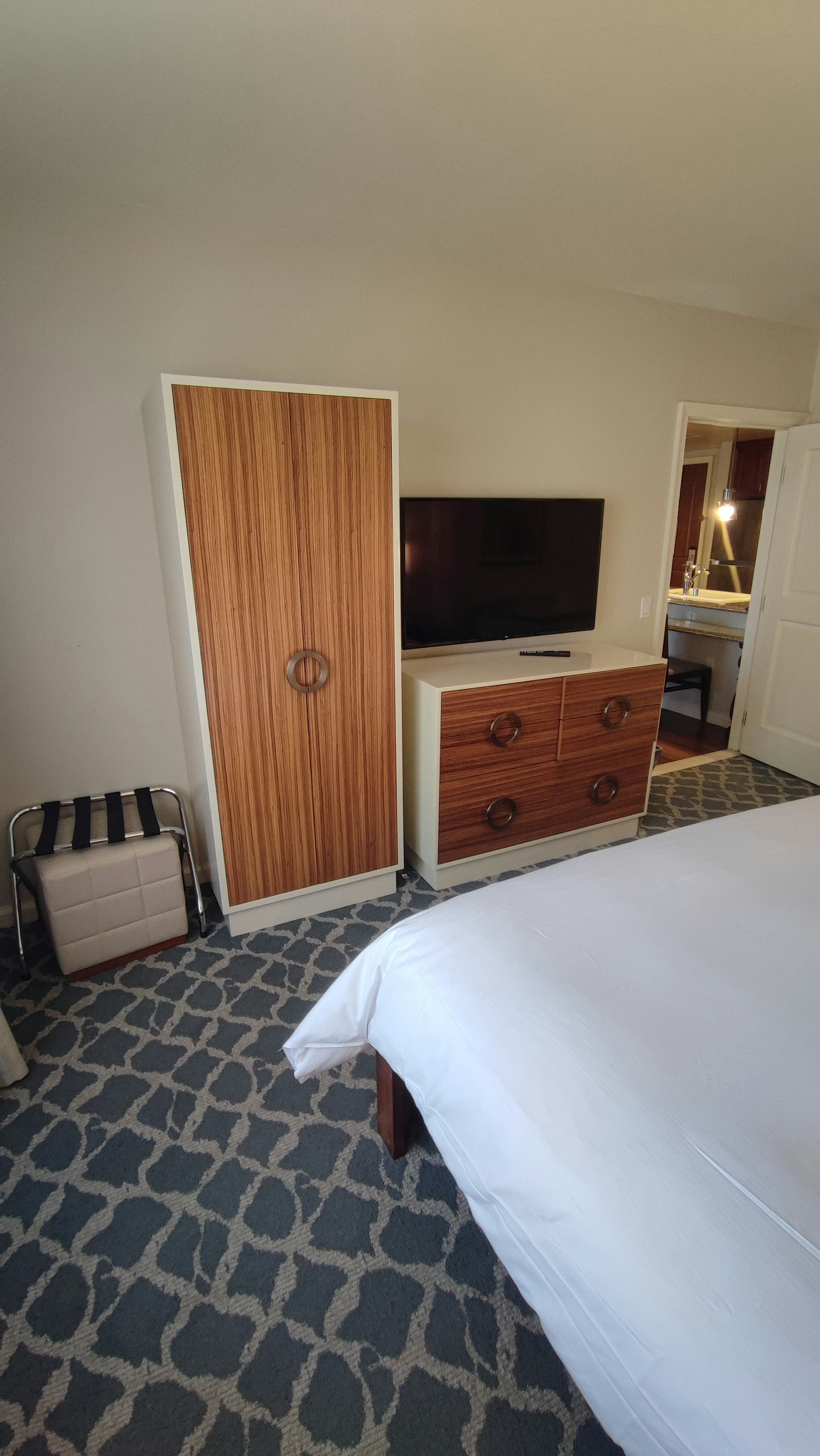 Brightly colored bedroom interior featuring a wooden wardrobe and a television with modern storage near the bed