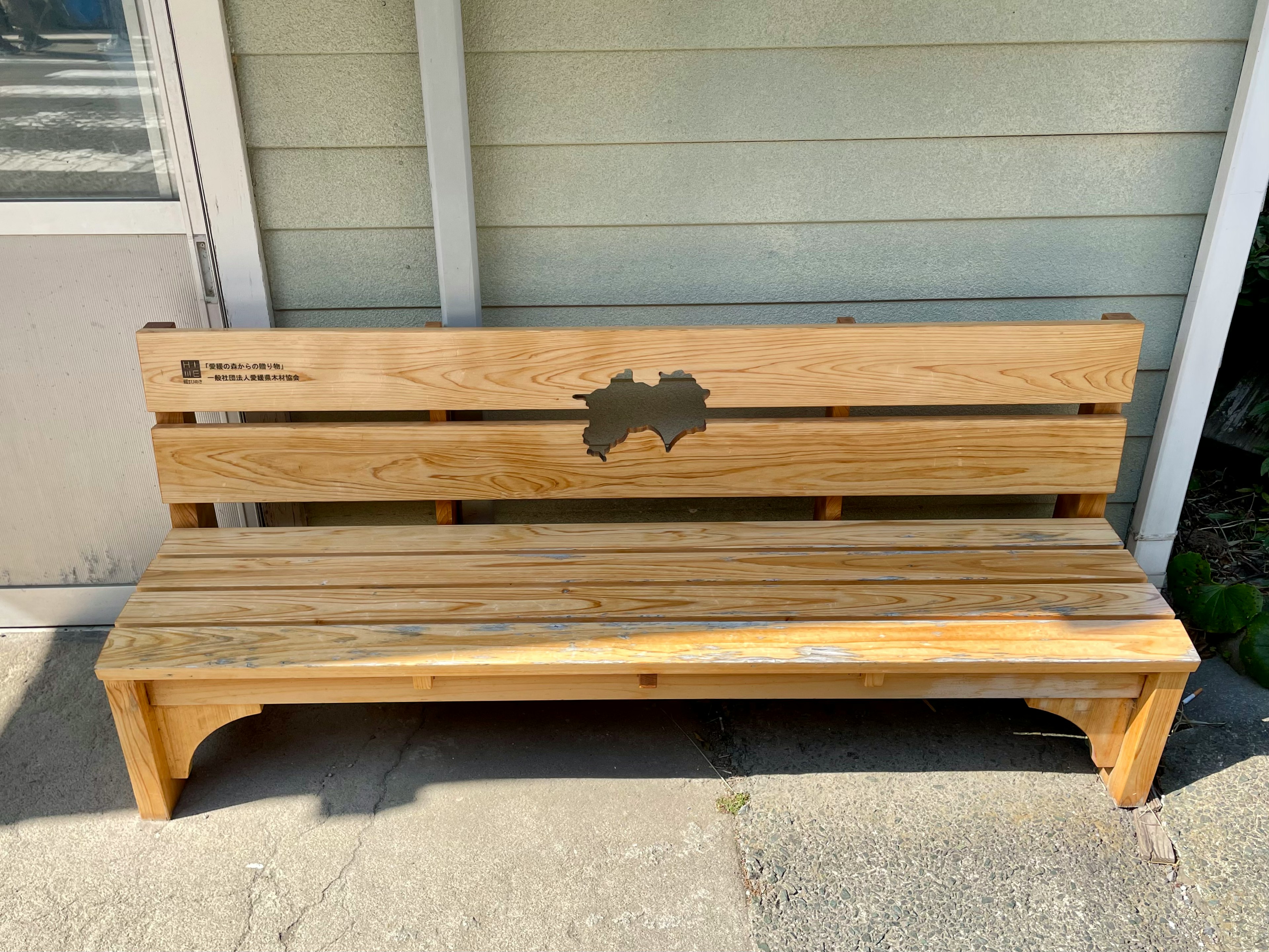 Wooden bench placed near a wall featuring a map design on the backrest