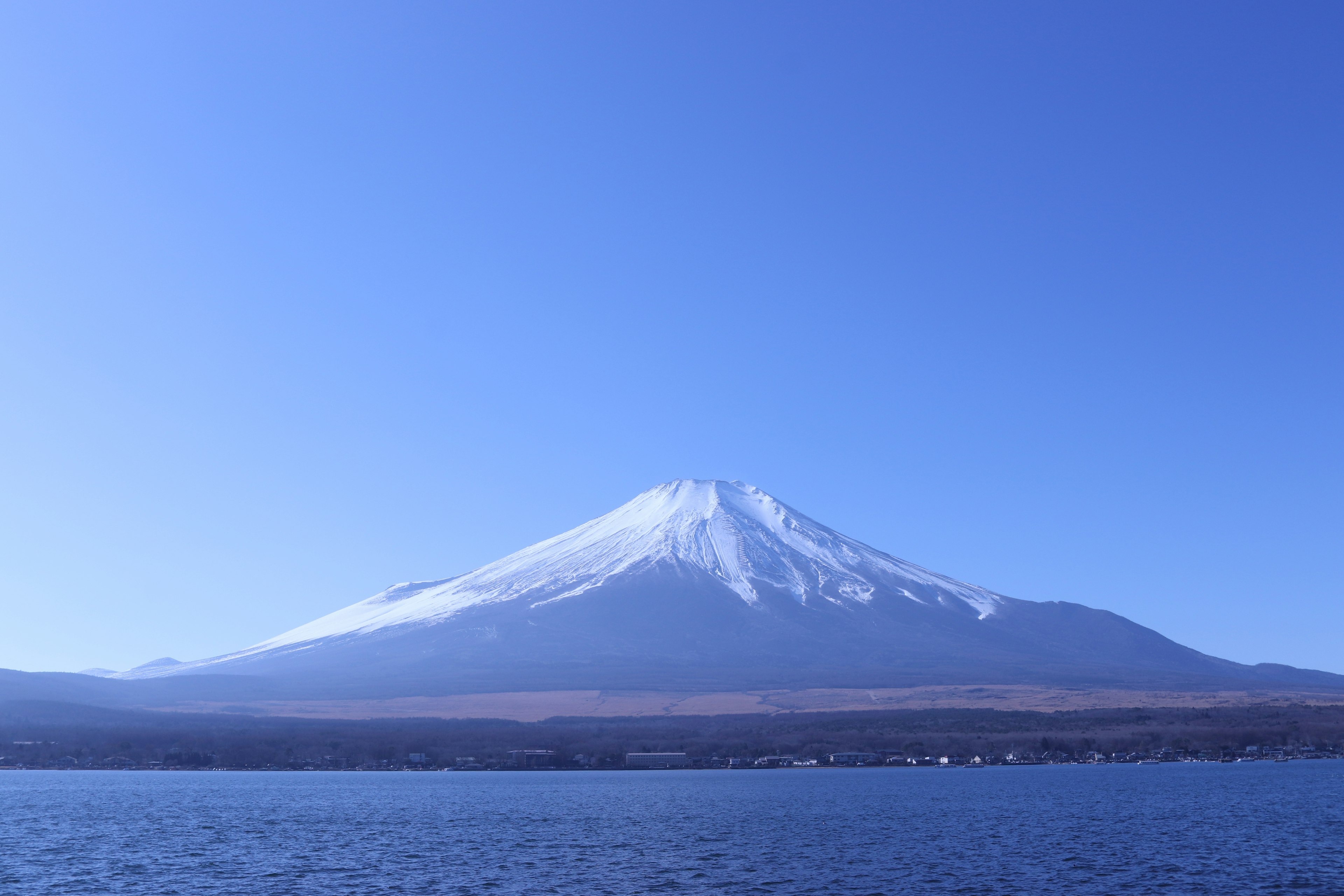 ทิวทัศน์ที่สวยงามของภูเขาฟูจิที่มีหิมะปกคลุมยอดเขาอยู่ใต้ท้องฟ้าสีฟ้าใส