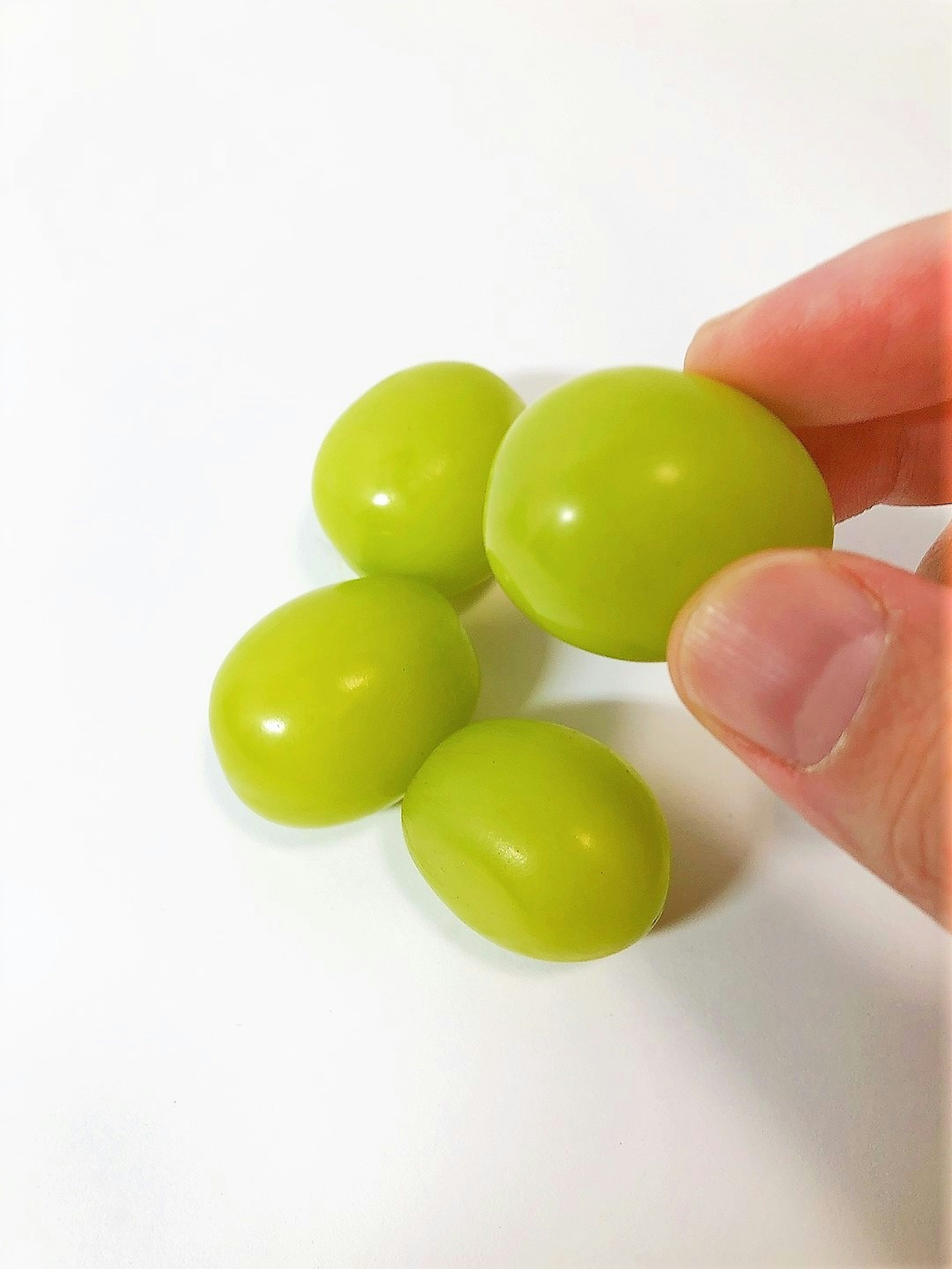 Image of green grapes held in hand against a white background