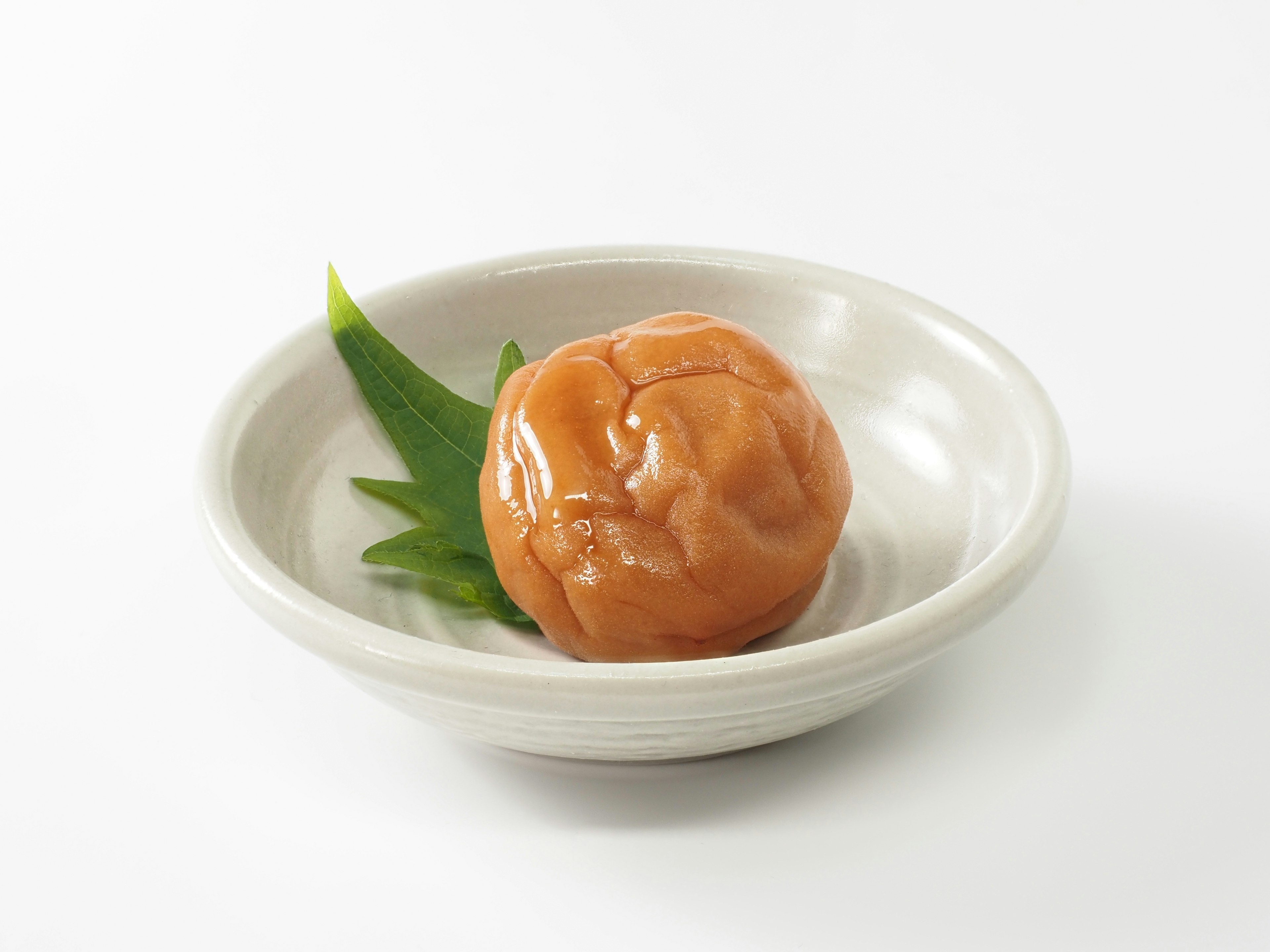 Umeboshi di piring putih dengan daun hijau