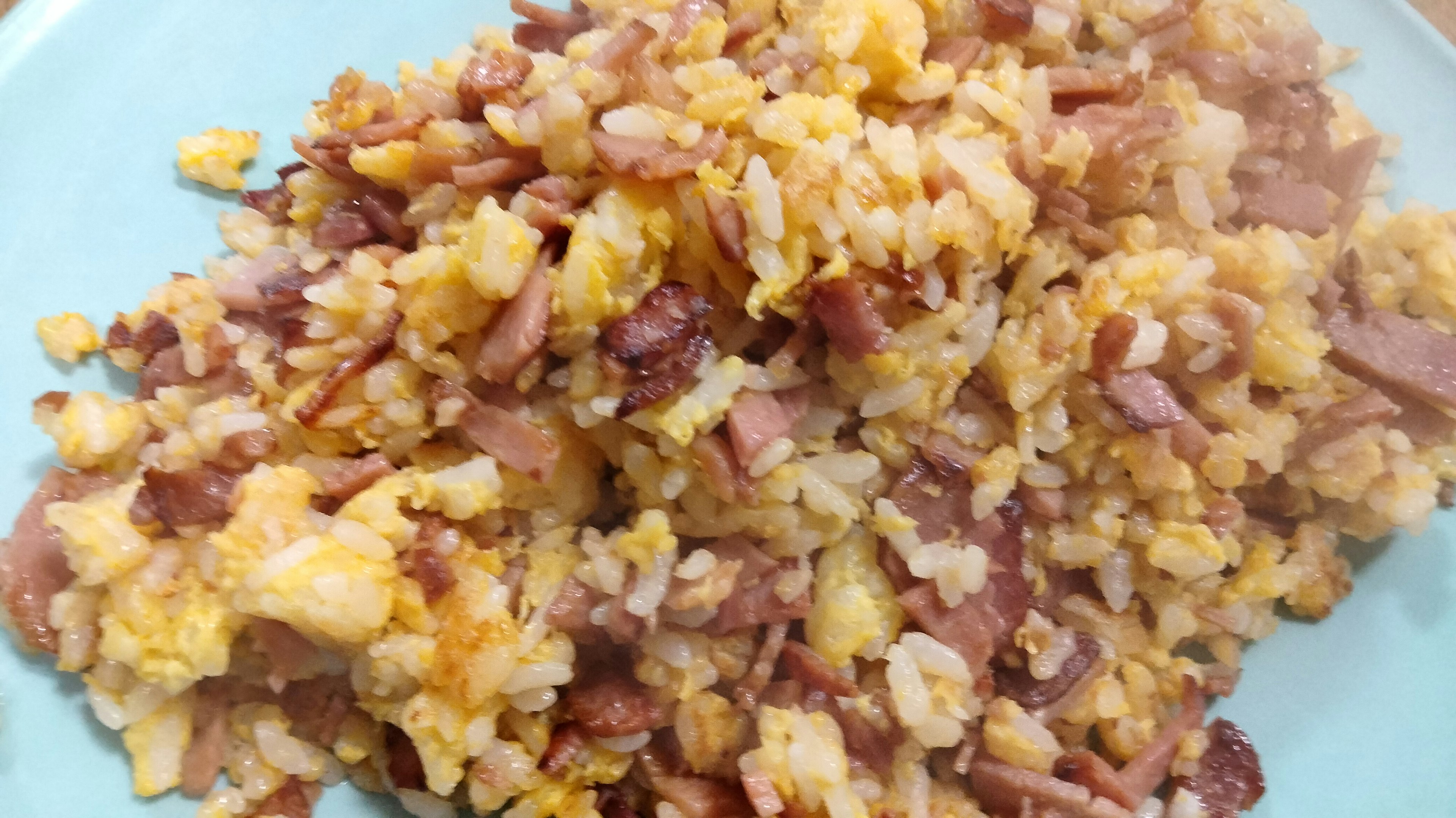 A plate of fried rice with scrambled eggs and ham