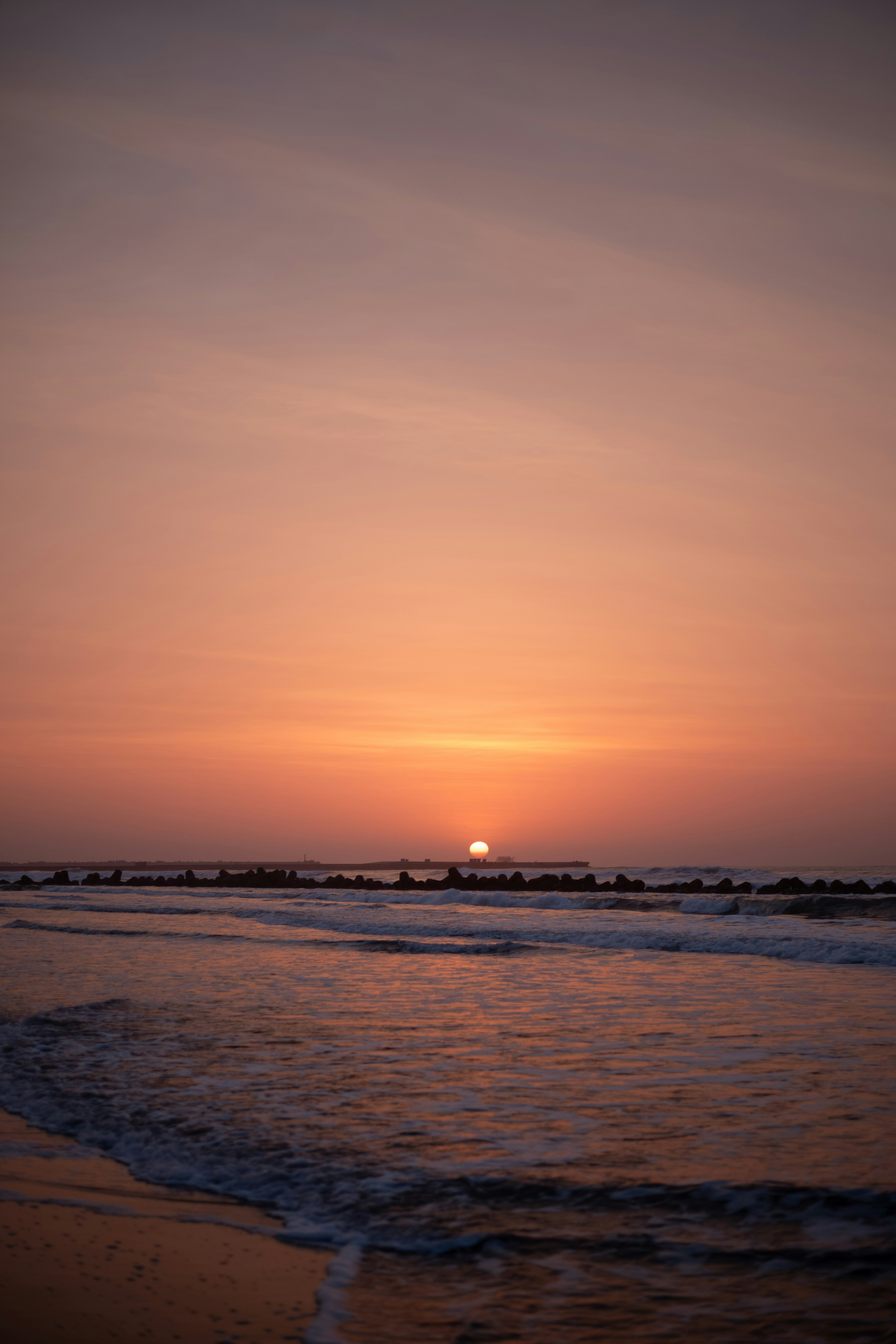 Coucher de soleil sur l'océan avec des vagues douces et un ciel tranquille