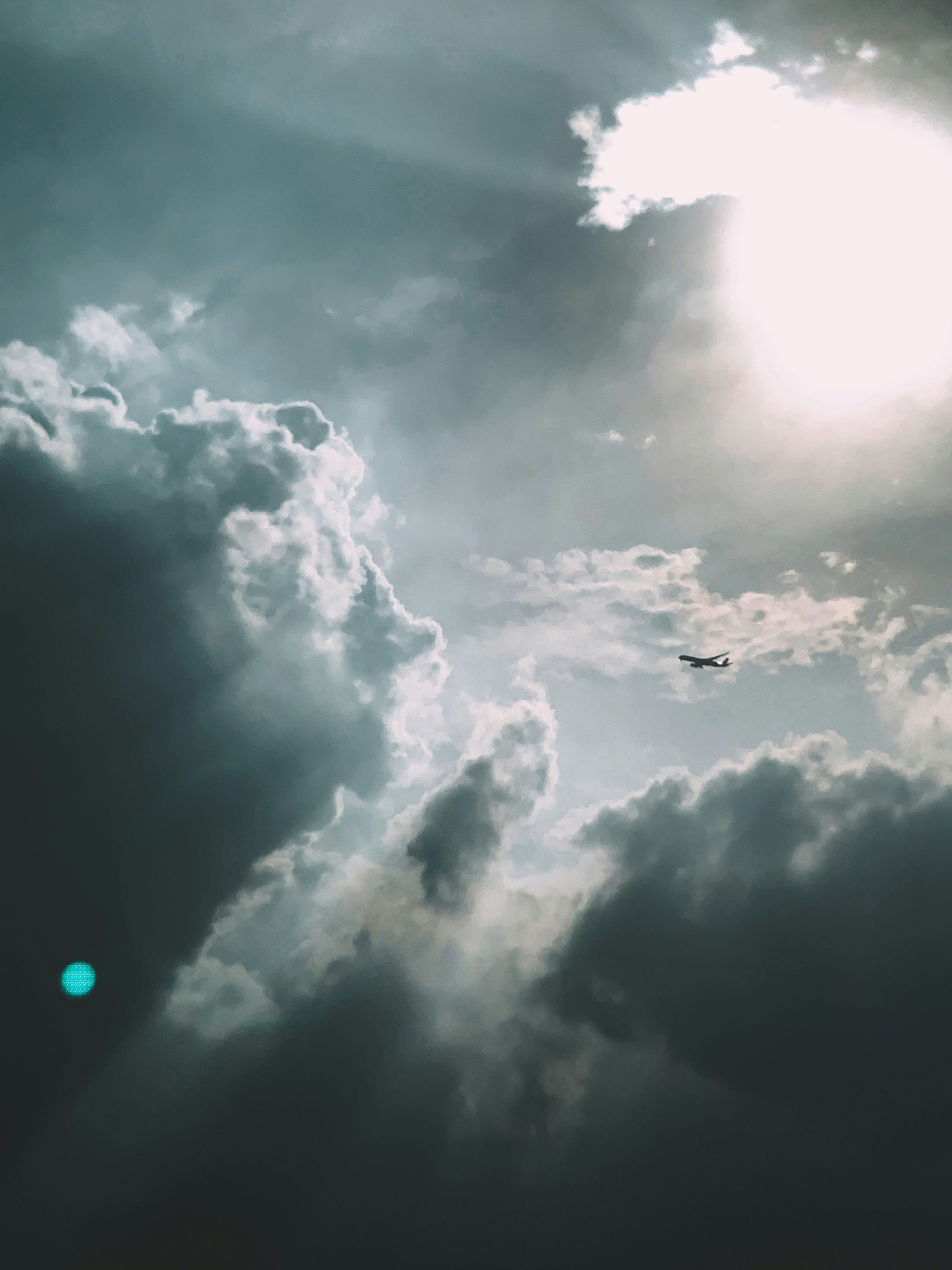 Silhouette of an airplane against a backdrop of blue sky and white clouds