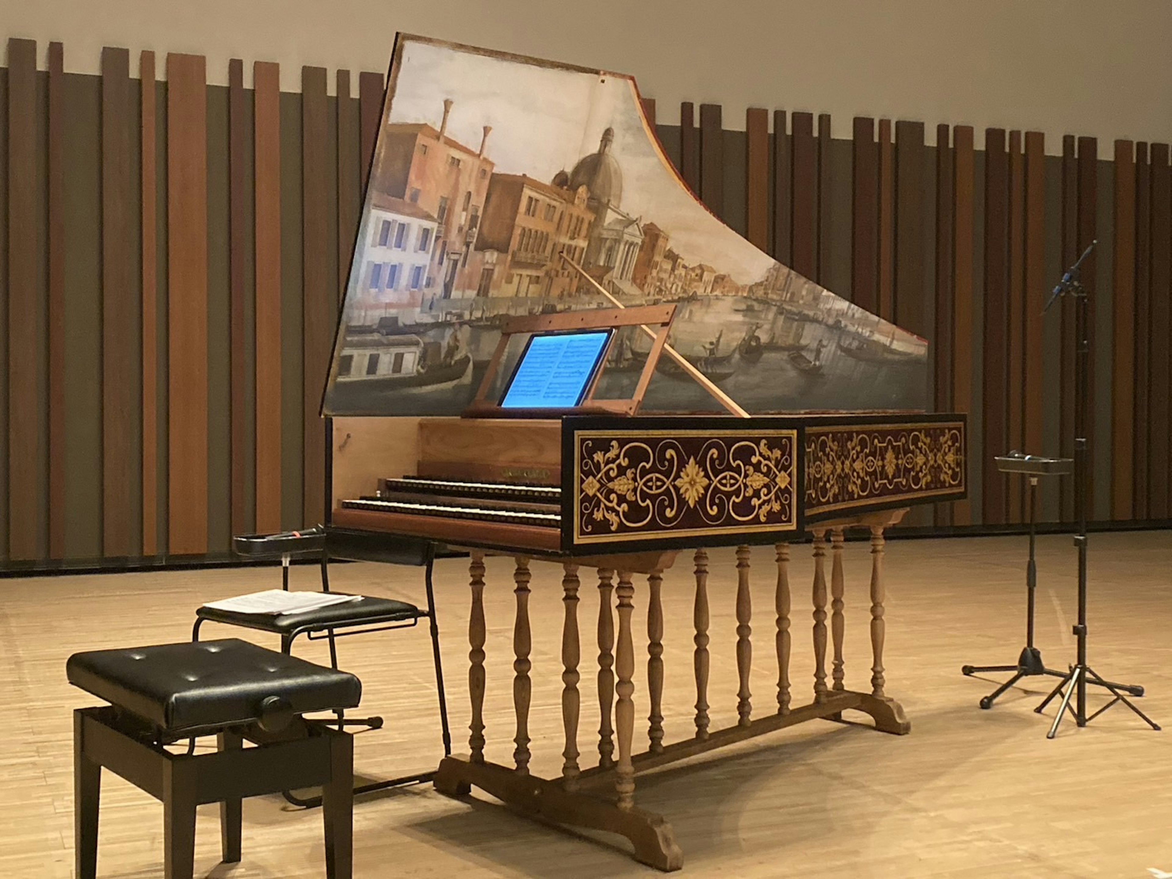 A beautifully decorated harpsichord displayed in a music hall interior