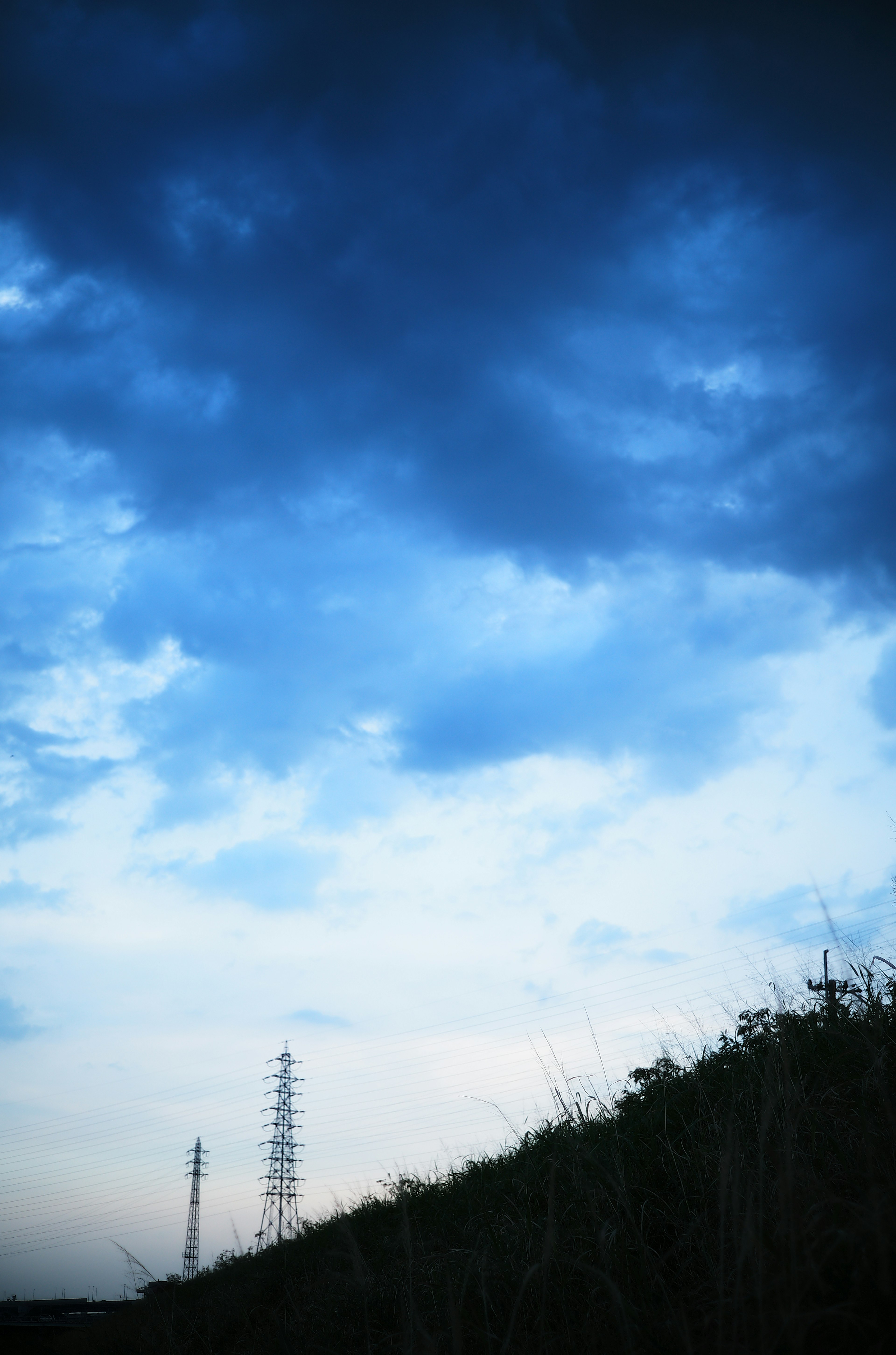 青い空と雲が広がる風景にシルエットの電柱