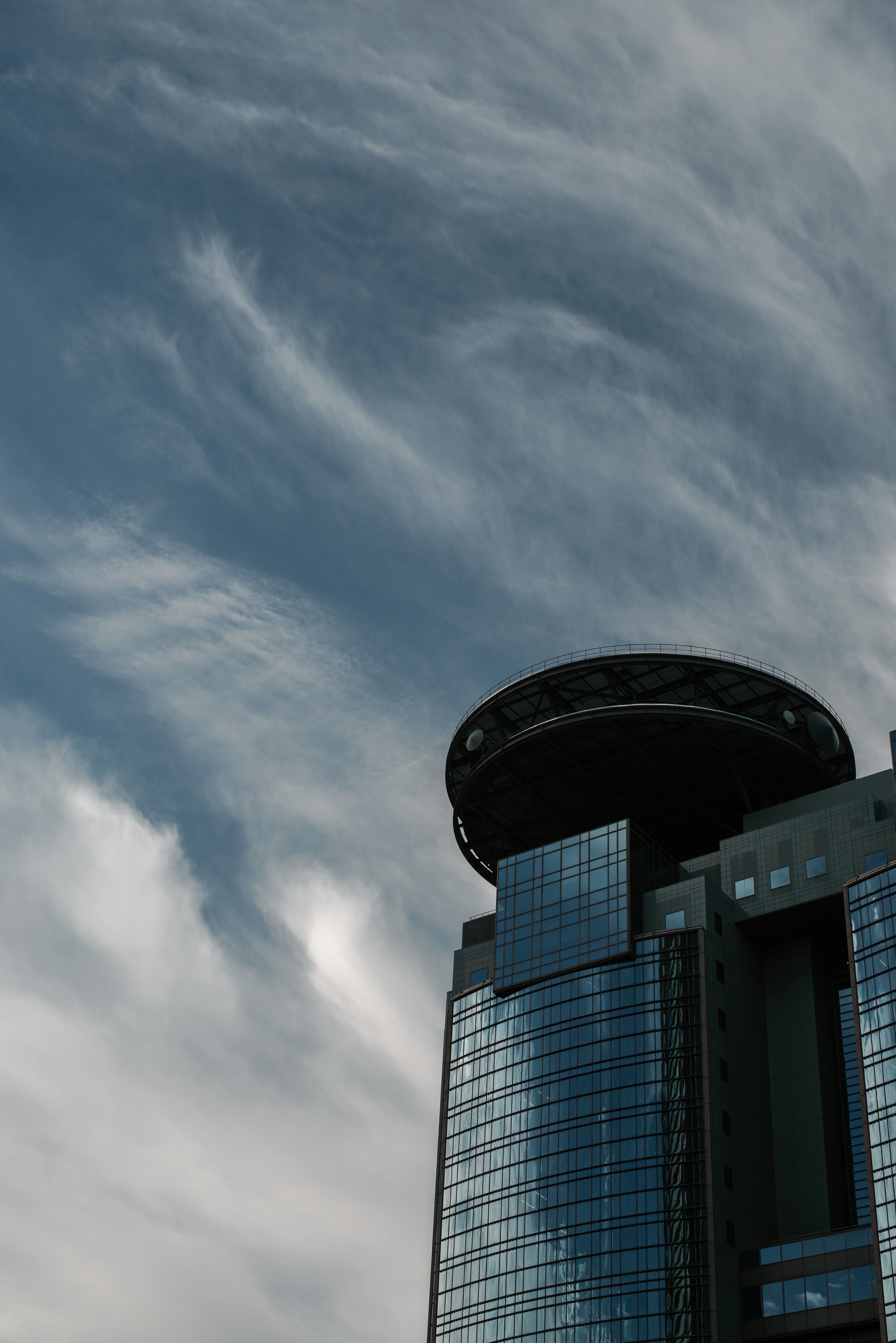 Top of a skyscraper against a cloudy blue sky