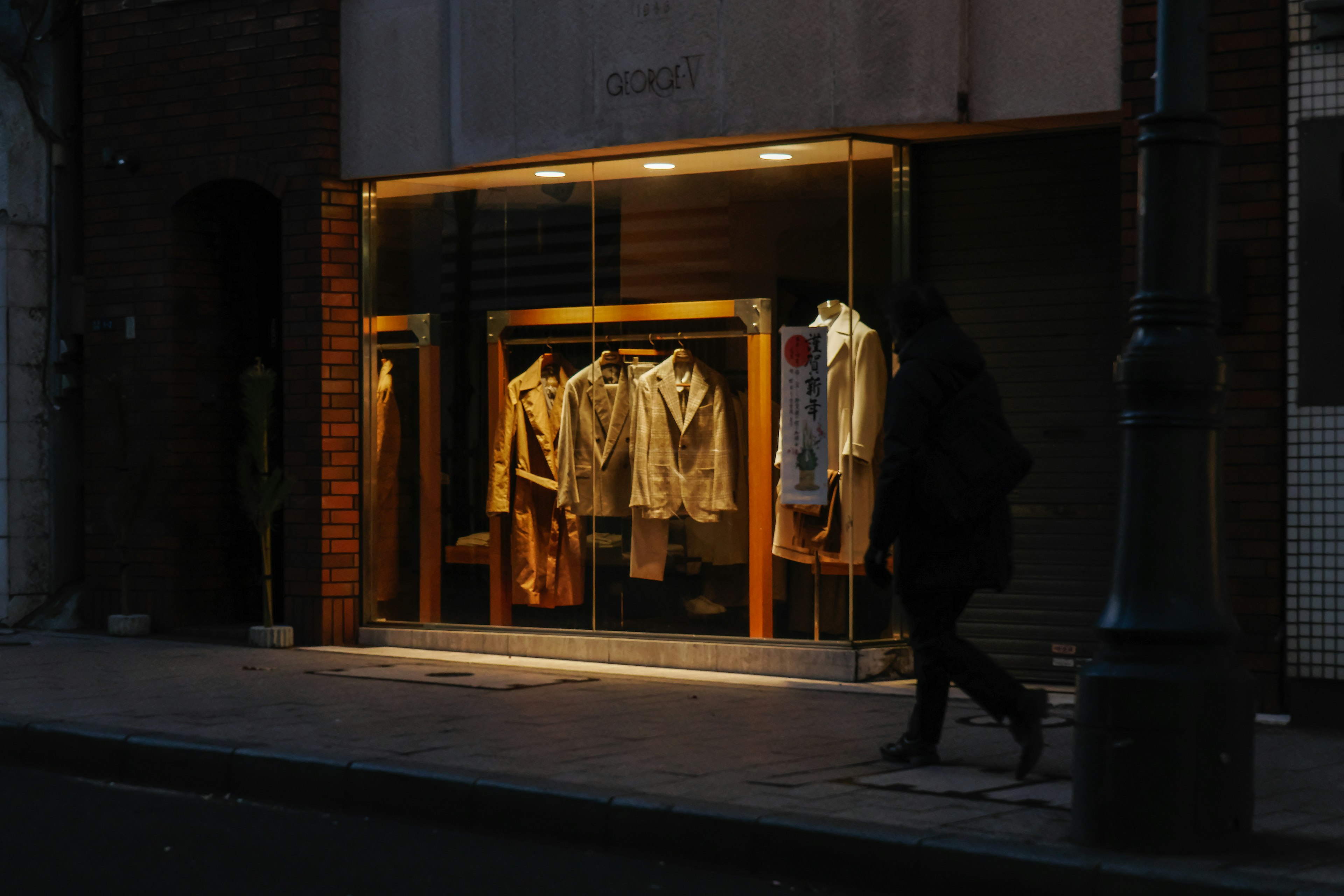 Clothing store window illuminated at night on a dim street