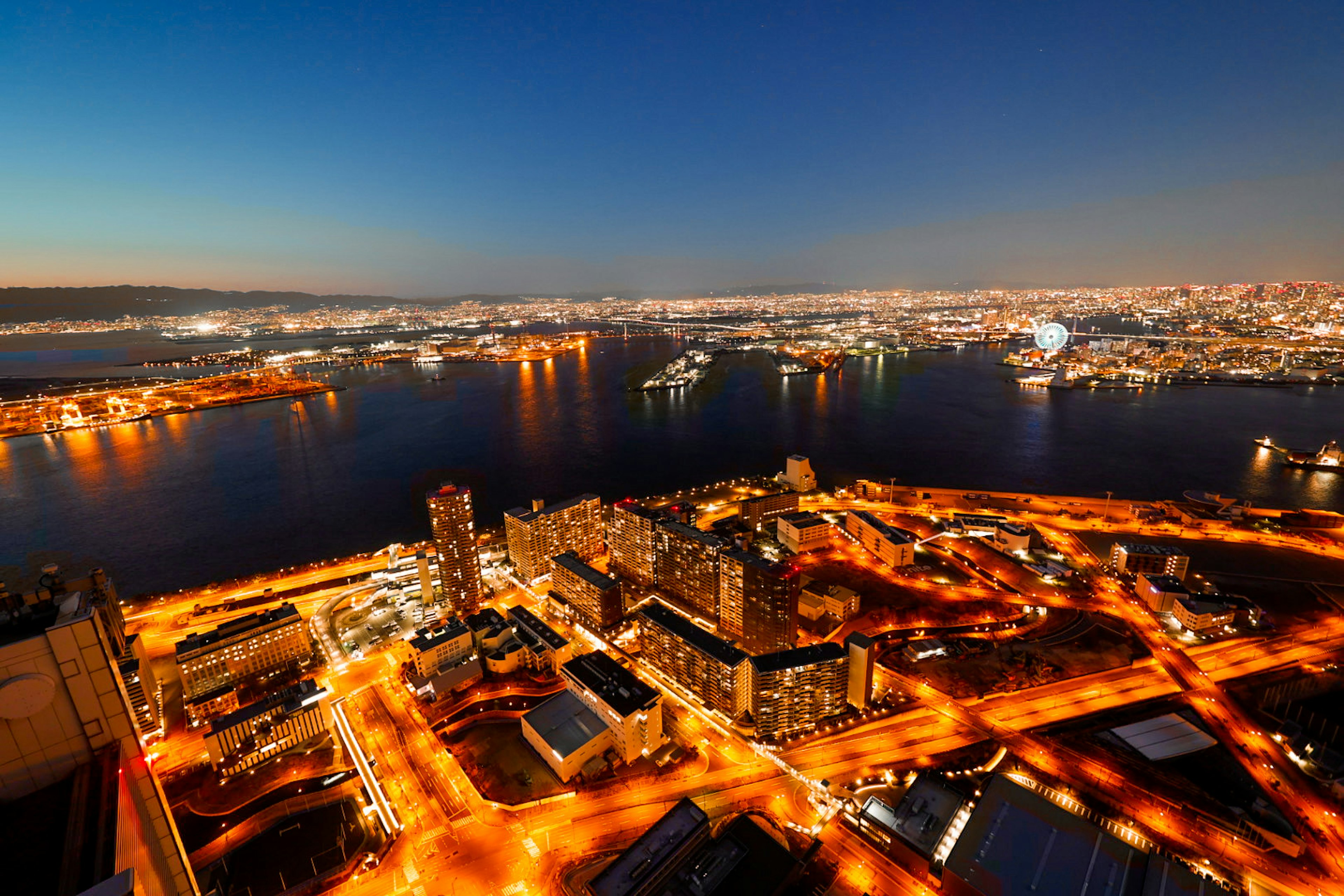 夜景の美しい港の上空からの眺めで、街の明かりが水面に反射している