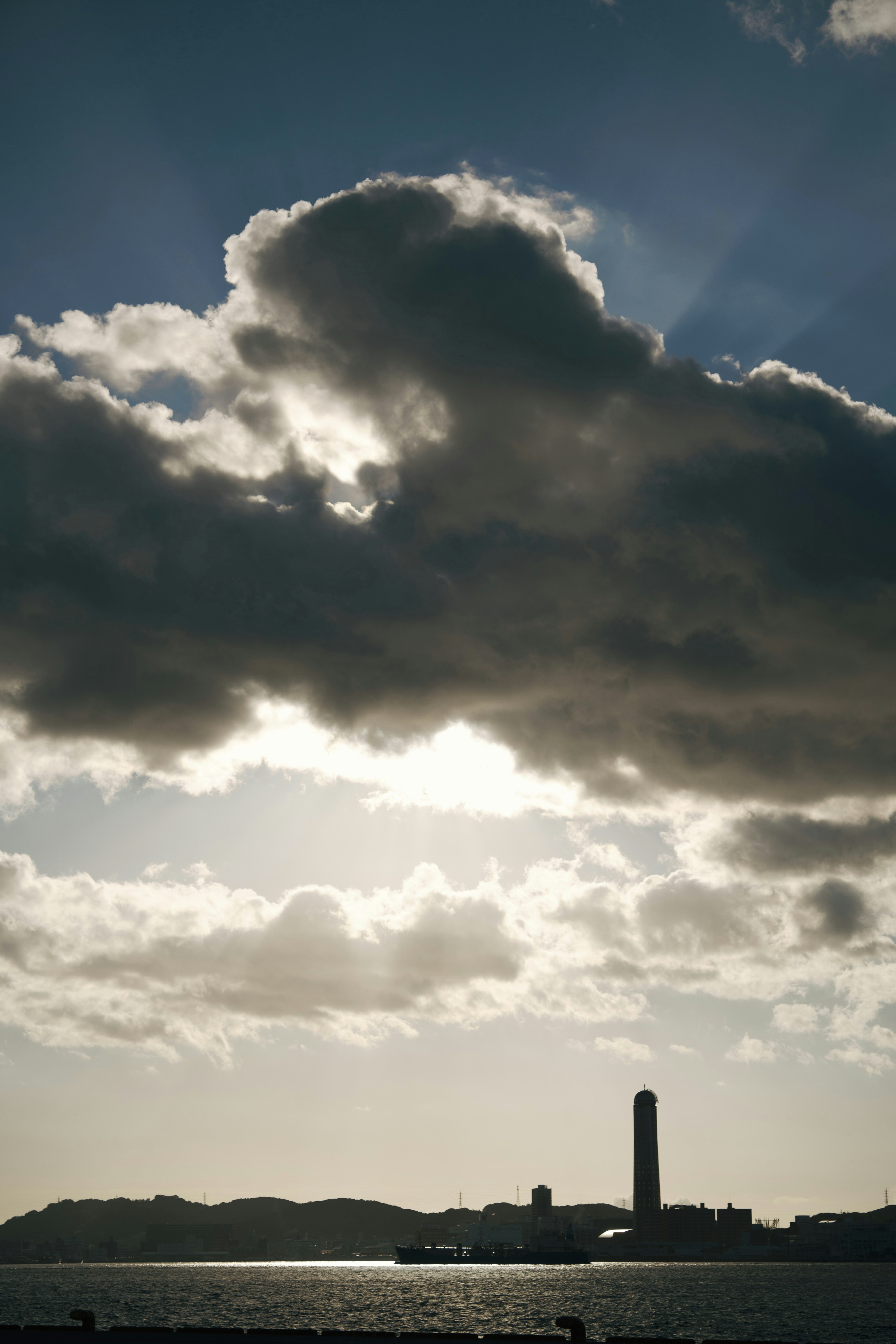 Silhouette di una torre contro un cielo nuvoloso sopra il mare