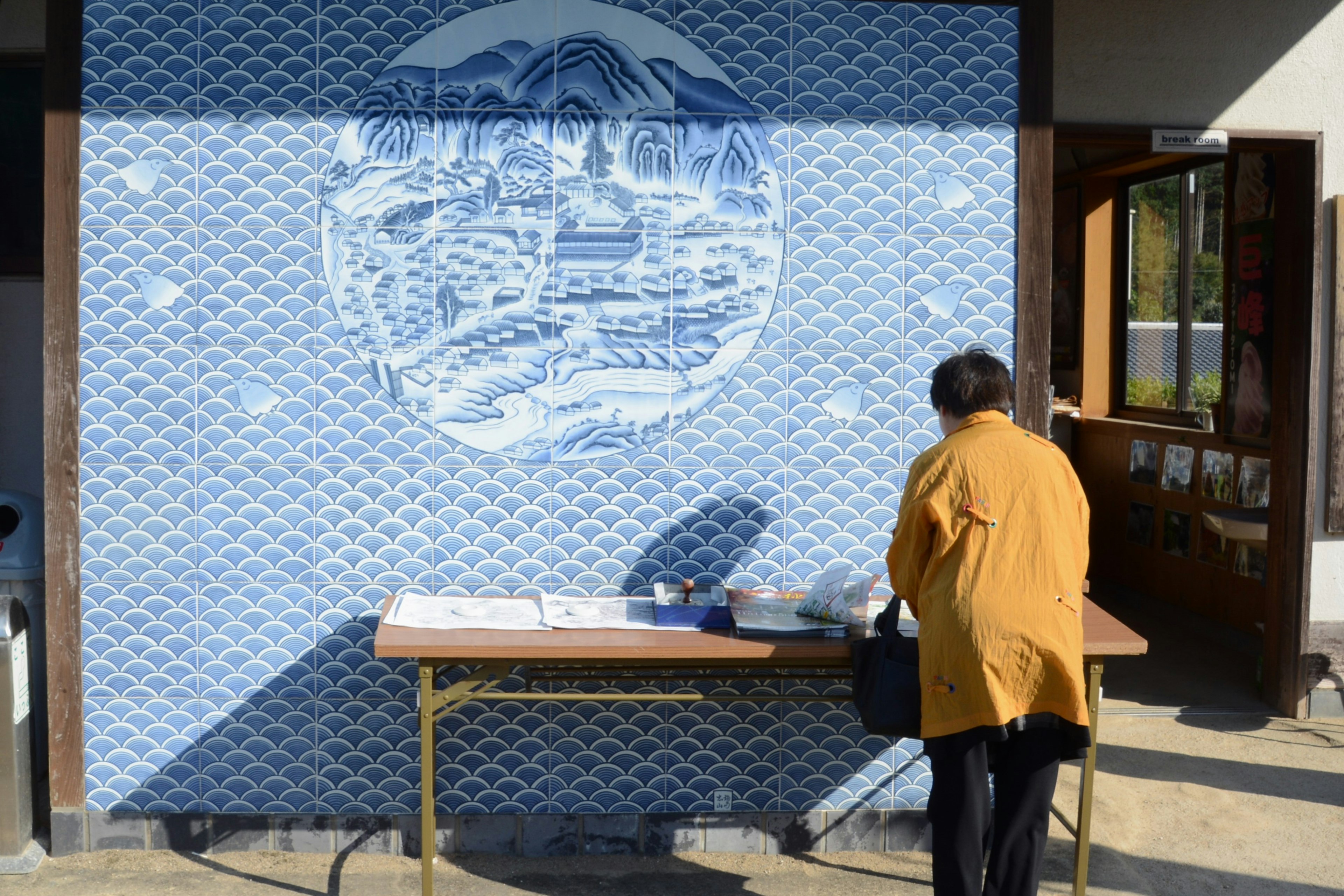 Persona che lavora a un tavolo di fronte a un murale blu