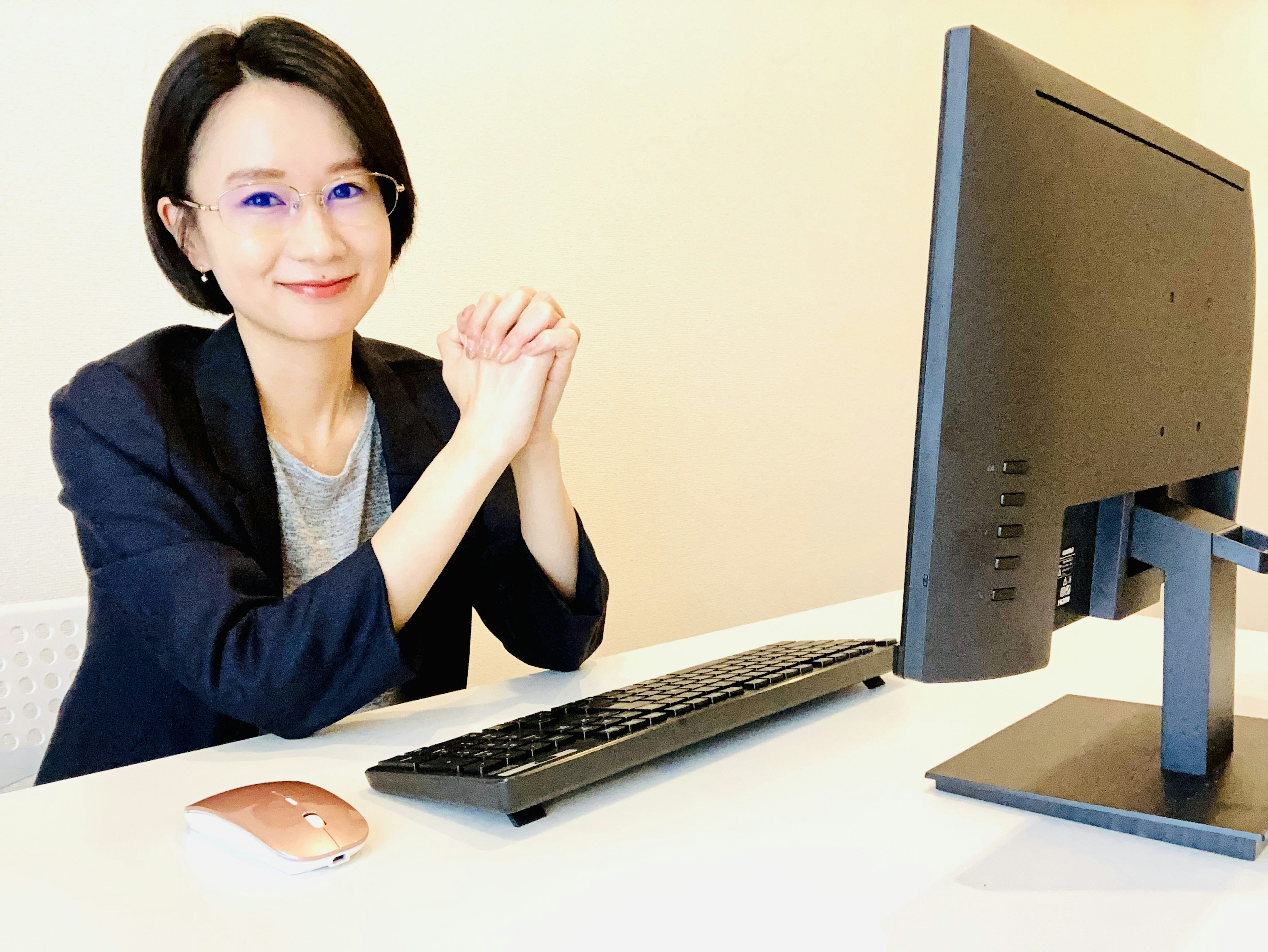 Una mujer sonriente sentada en un escritorio frente a una computadora