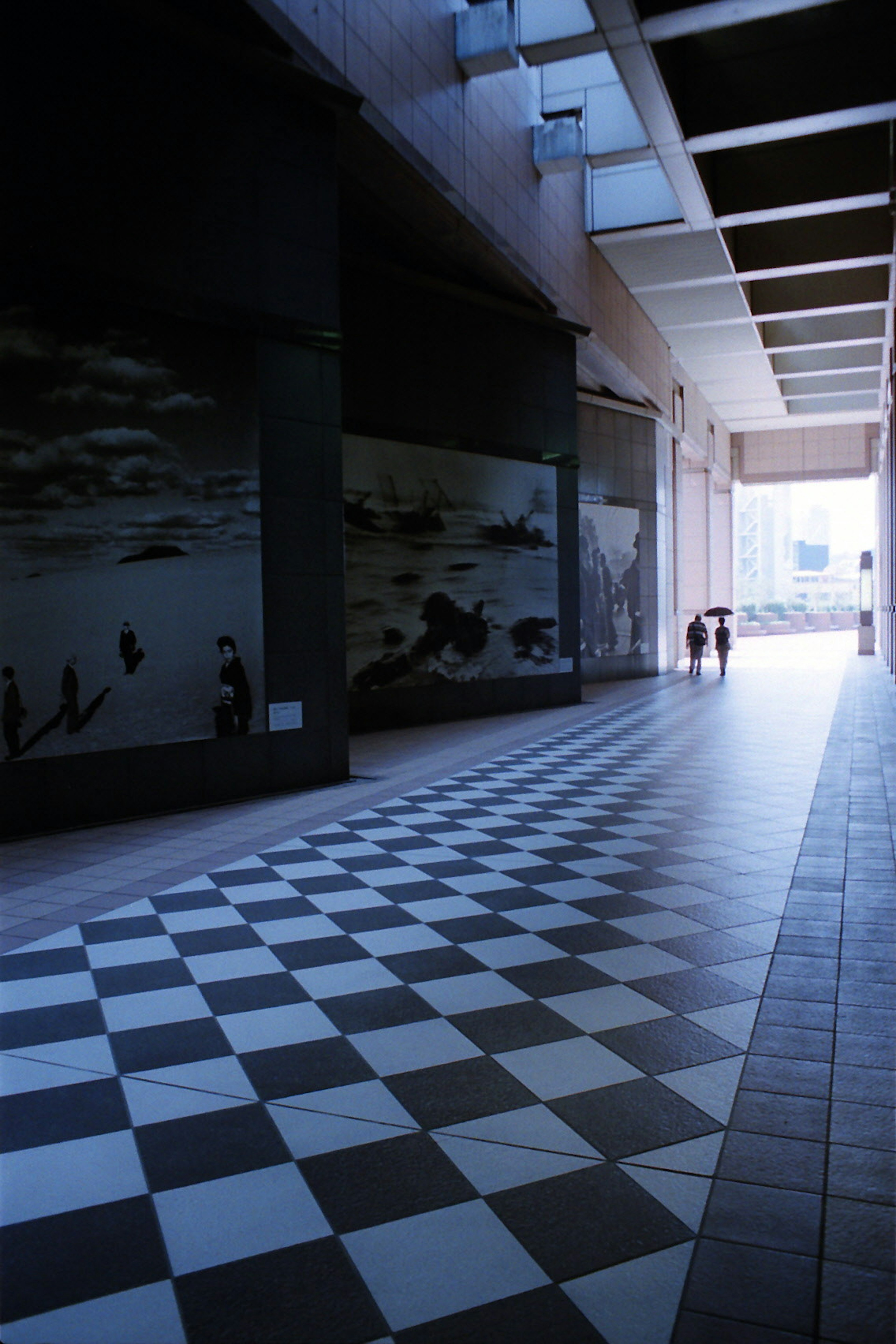 Image d'un couloir avec un sol en damier noir et blanc et des peintures murales sur les murs