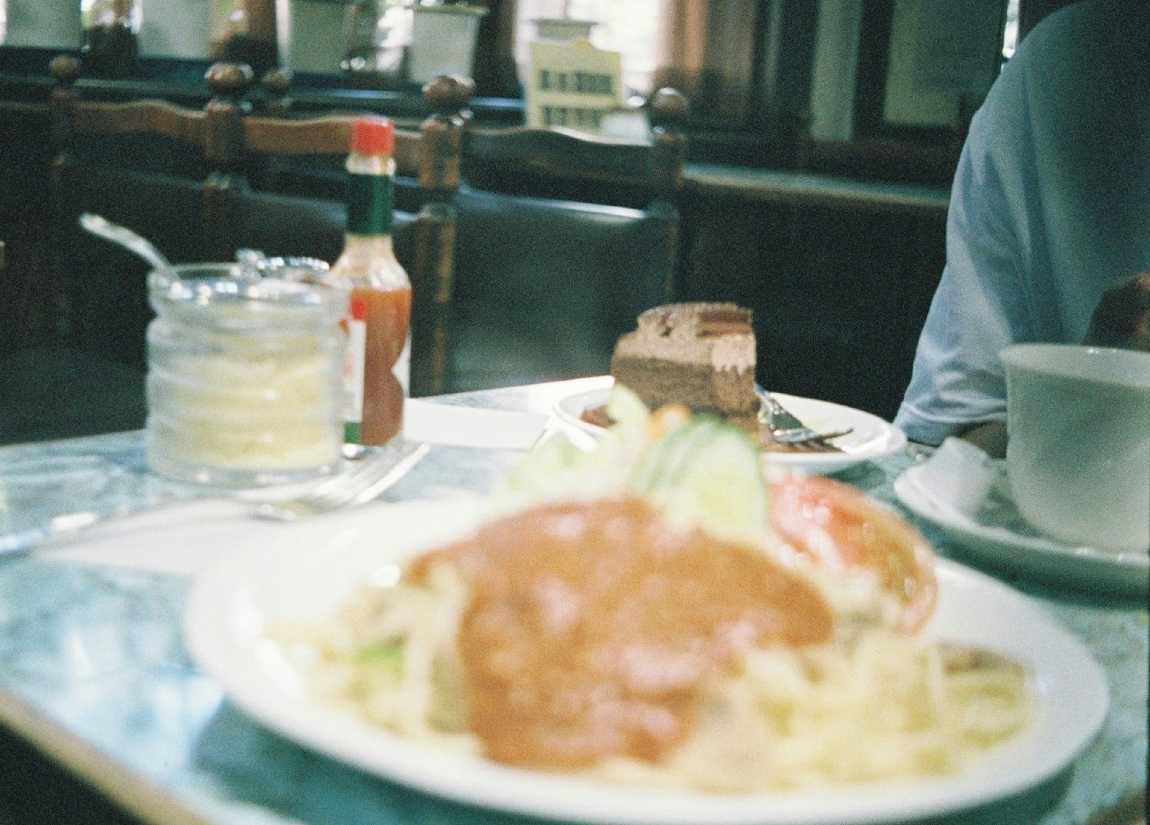 テーブルに置かれた料理と飲み物の写真 サラダとソースがトッピングされた料理がメイン