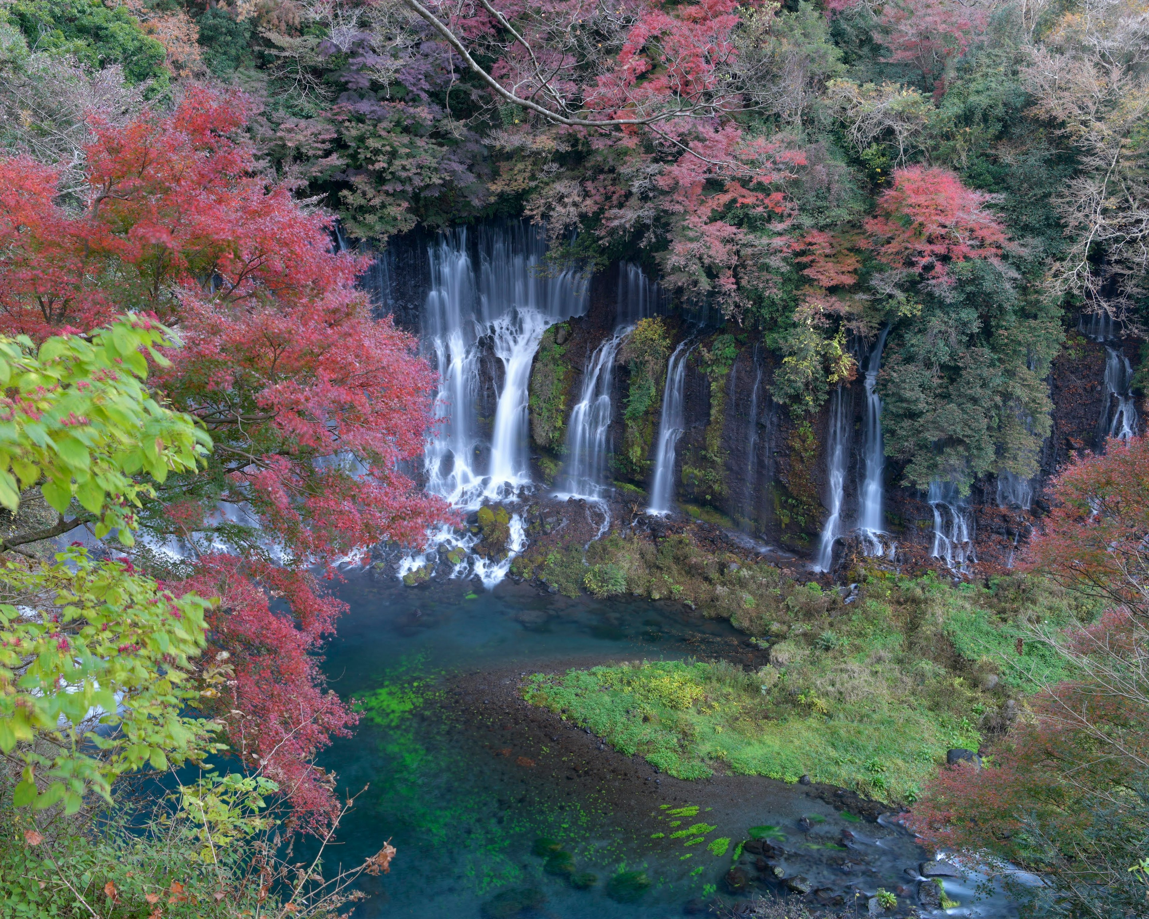 Malersicher Blick auf Wasserfälle umgeben von buntem Herbstlaub