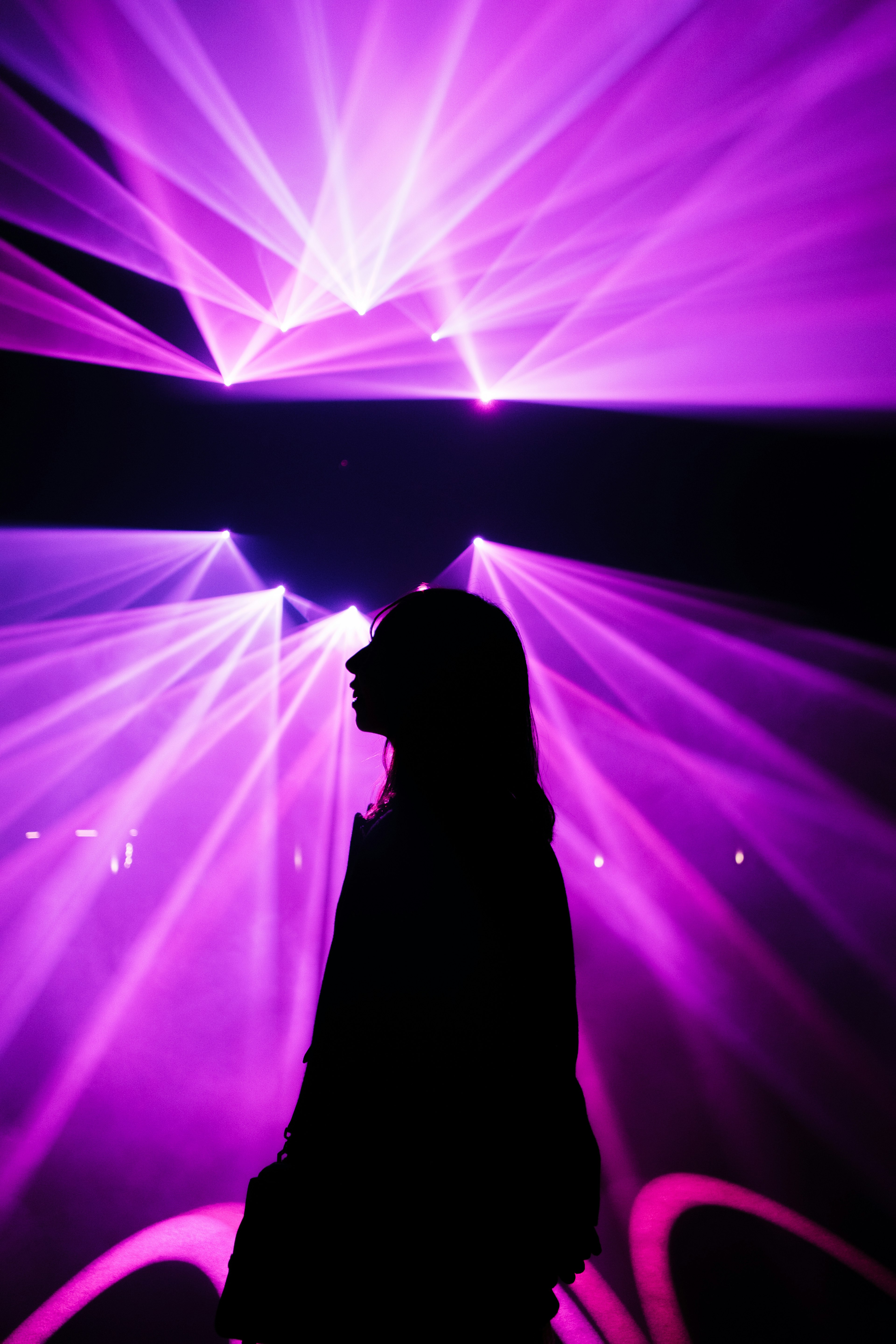 Silhouette d'une personne contre des lumières laser violettes dans un cadre de club