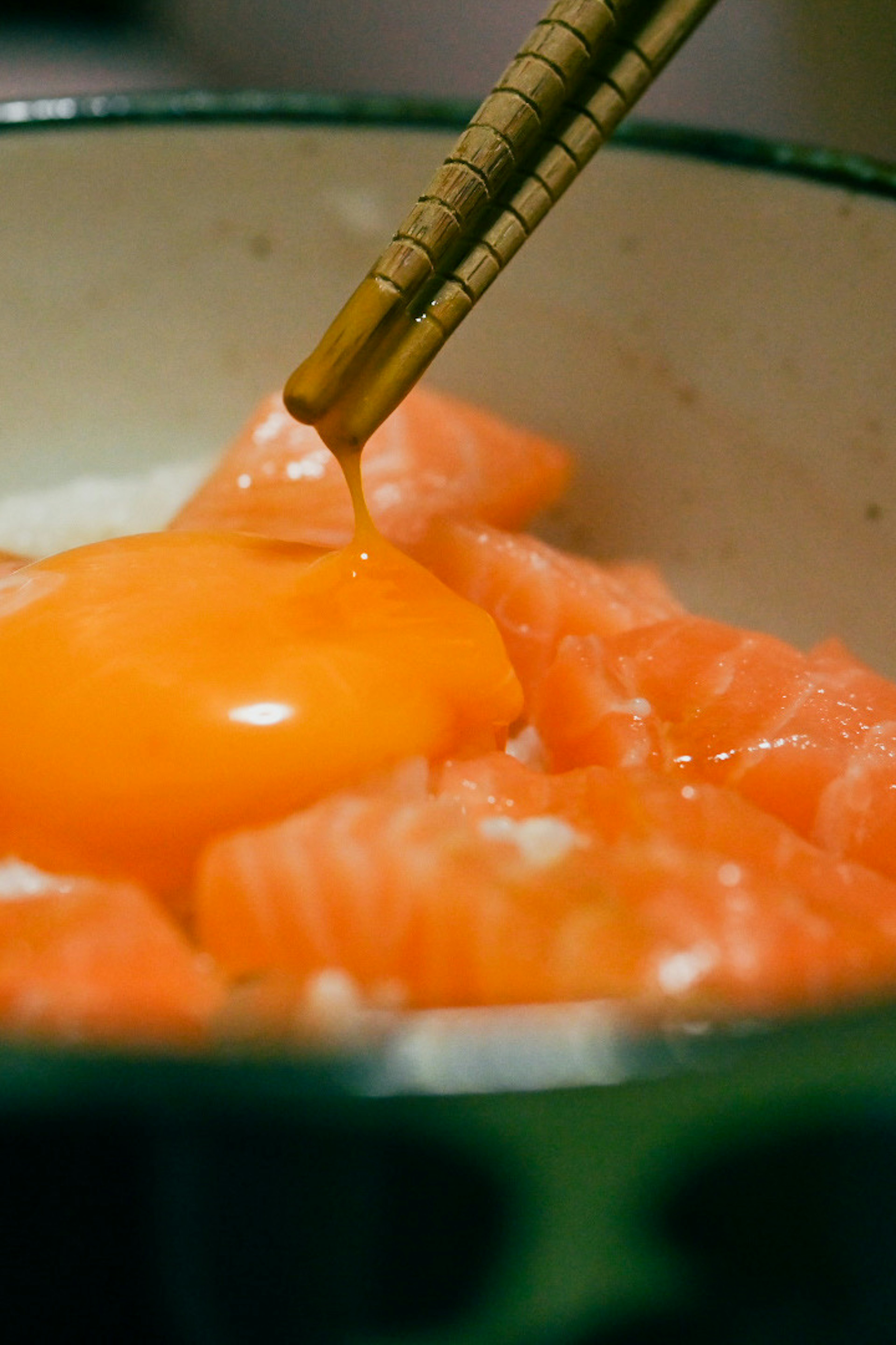 Close-up of salmon sashimi topped with an egg yolk in a bowl