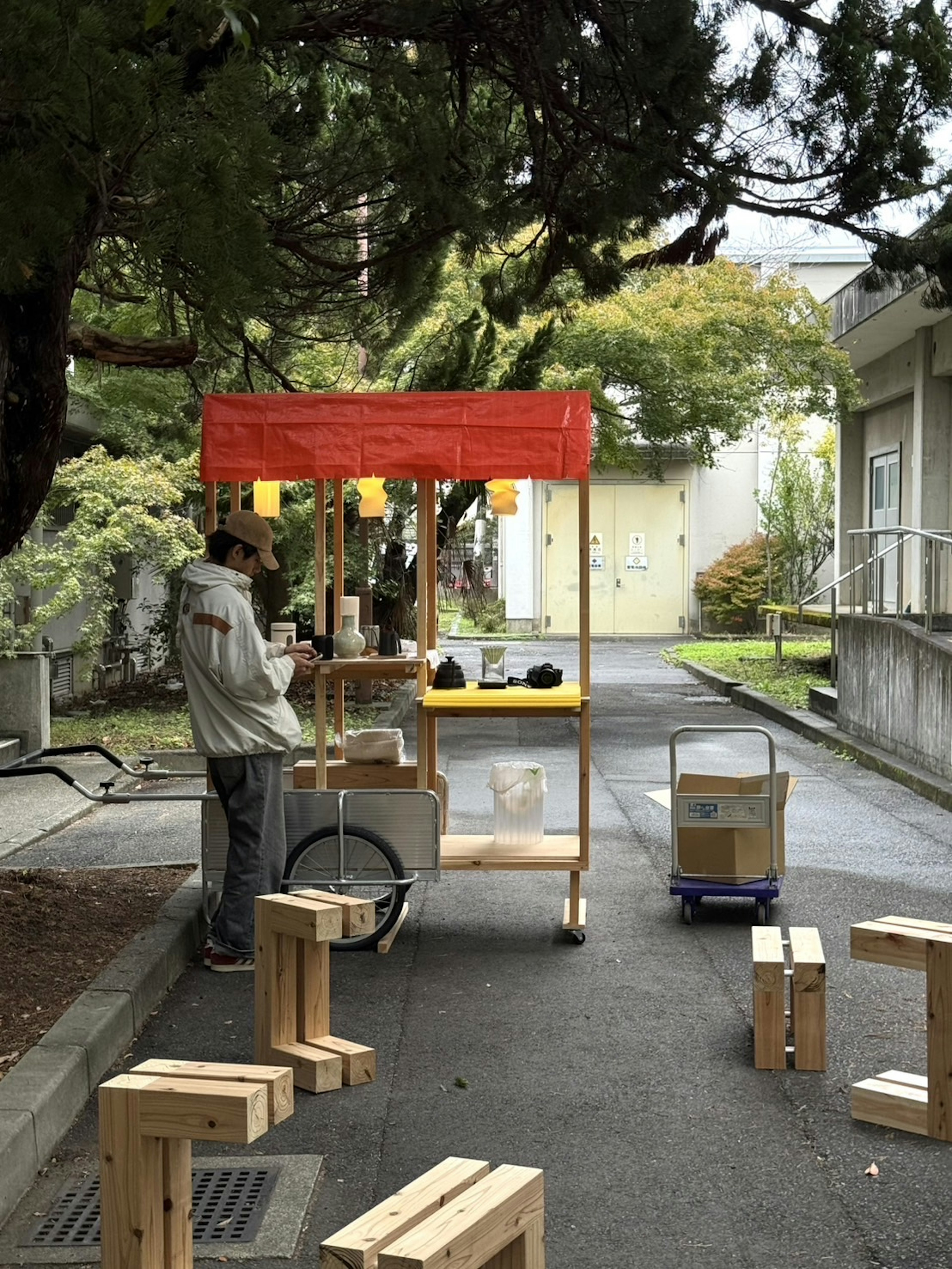 赤い屋根の屋台で作業する男性 周囲には木製の椅子と箱がある