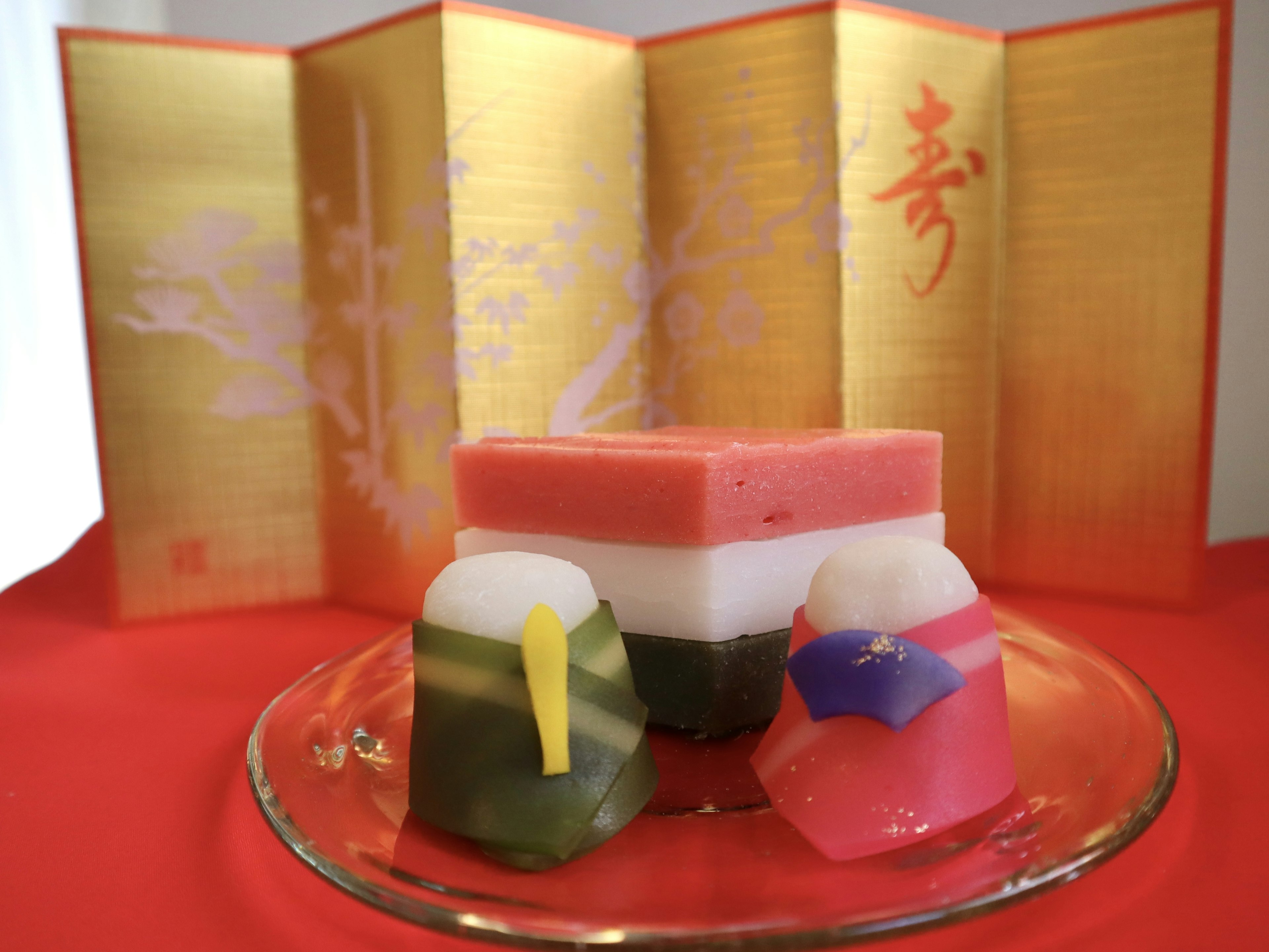 Colorful Japanese sweets arranged on a glass plate with a gold folding screen