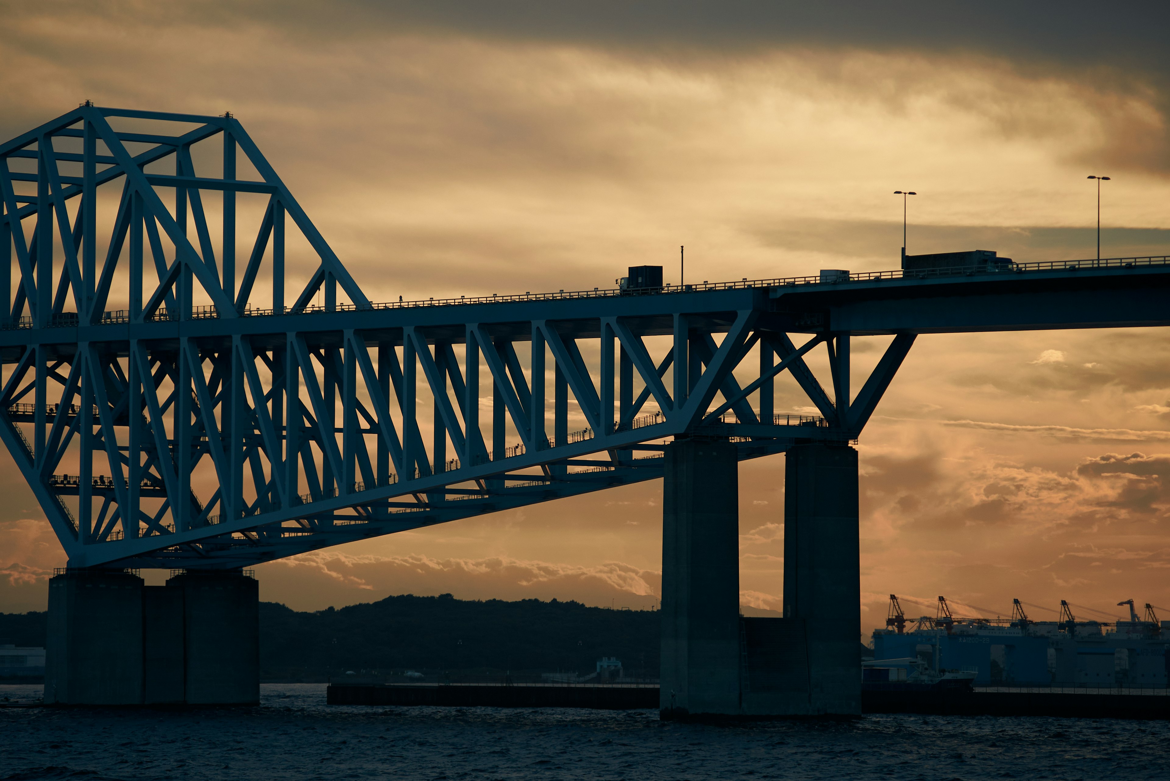 Siluet jembatan saat matahari terbenam dengan awan di latar belakang