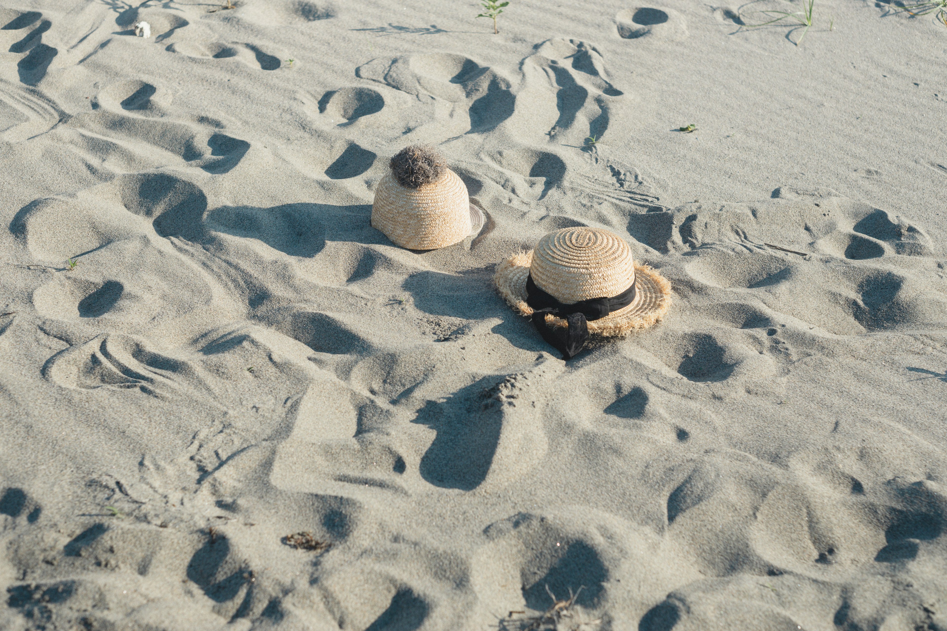 Deux chapeaux sur la plage avec des empreintes dans le sable