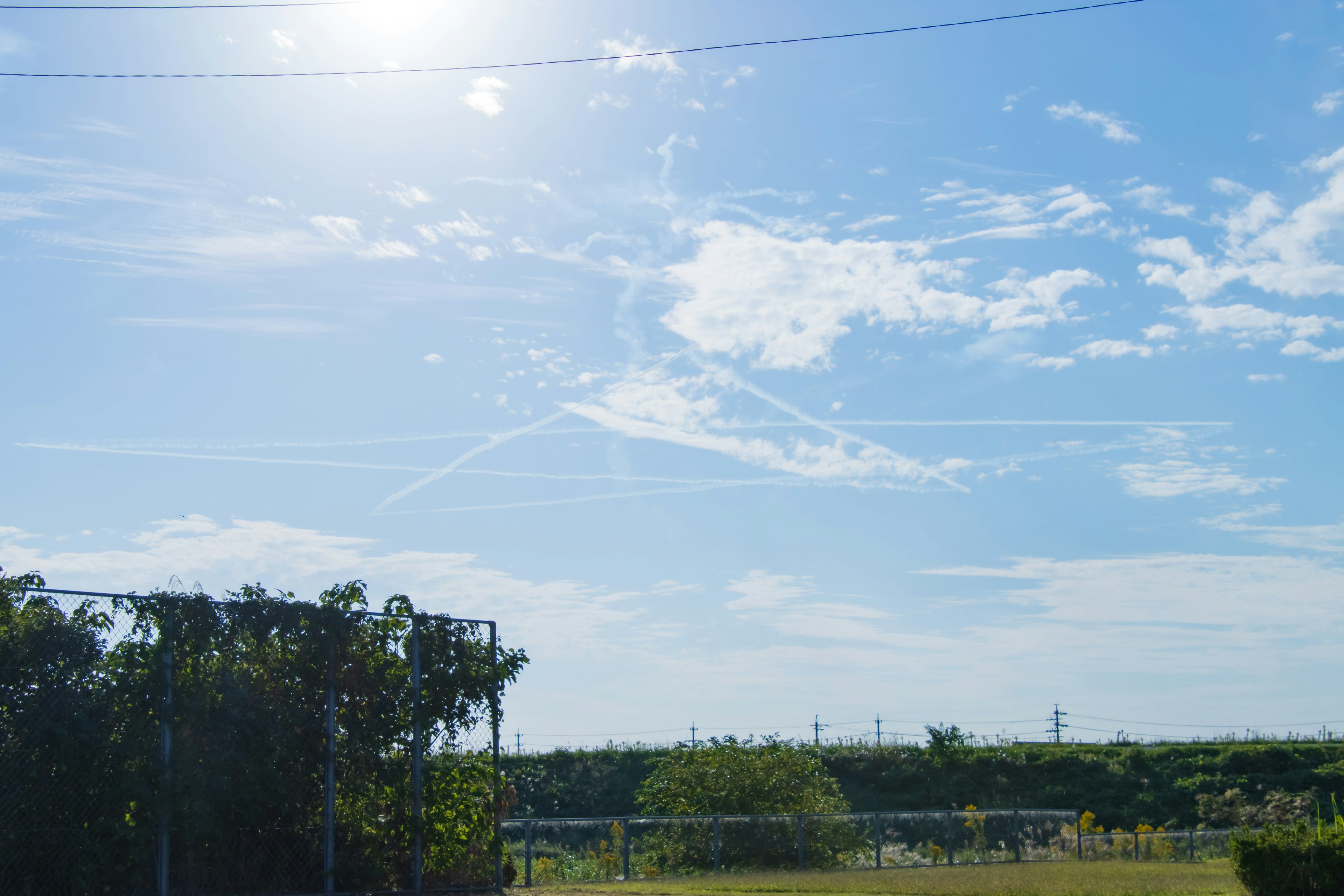 青空に白い雲が広がり太陽が輝いている風景