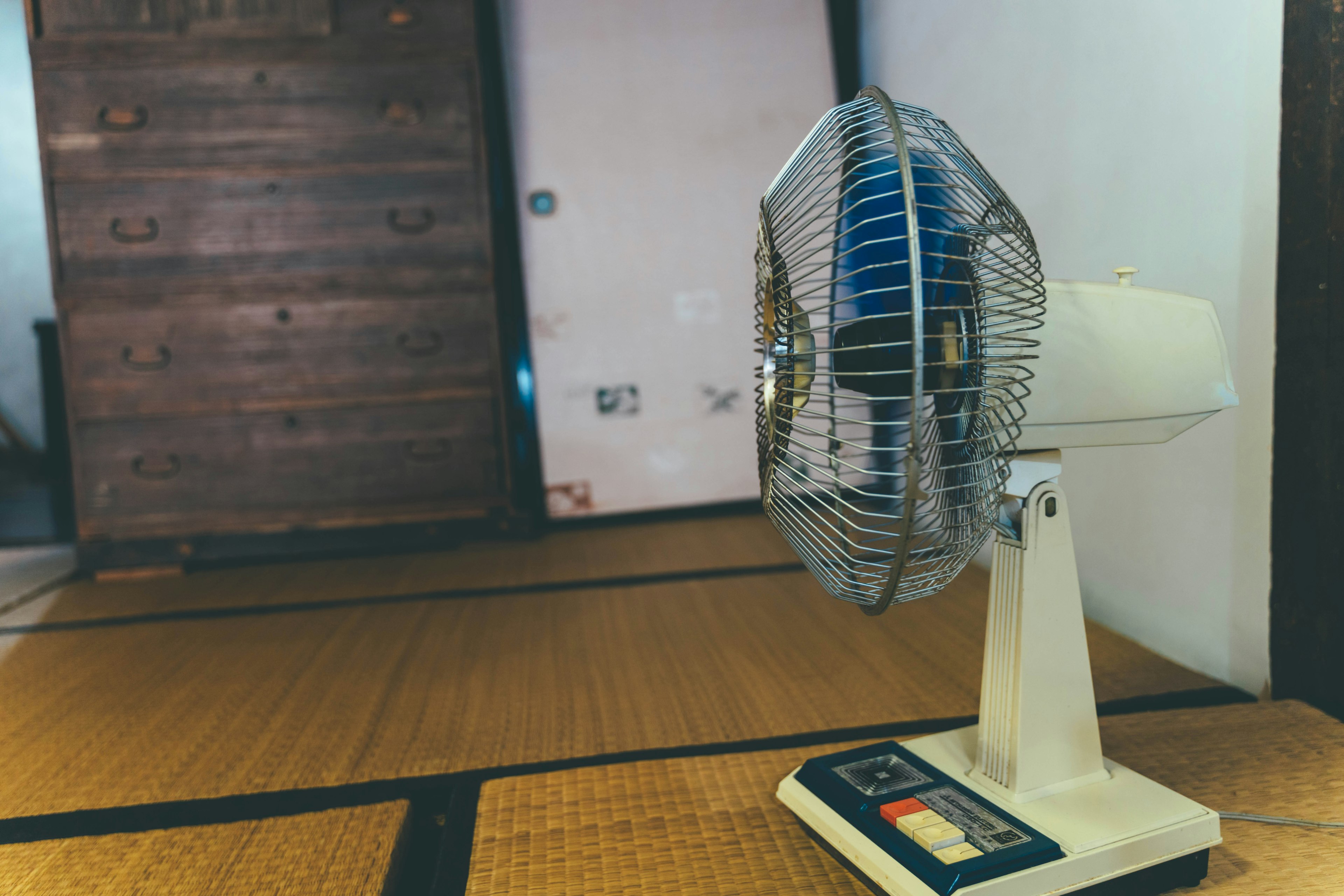 Ein vintage Tischventilator steht auf einem Tatami-Boden in einem traditionellen Raum