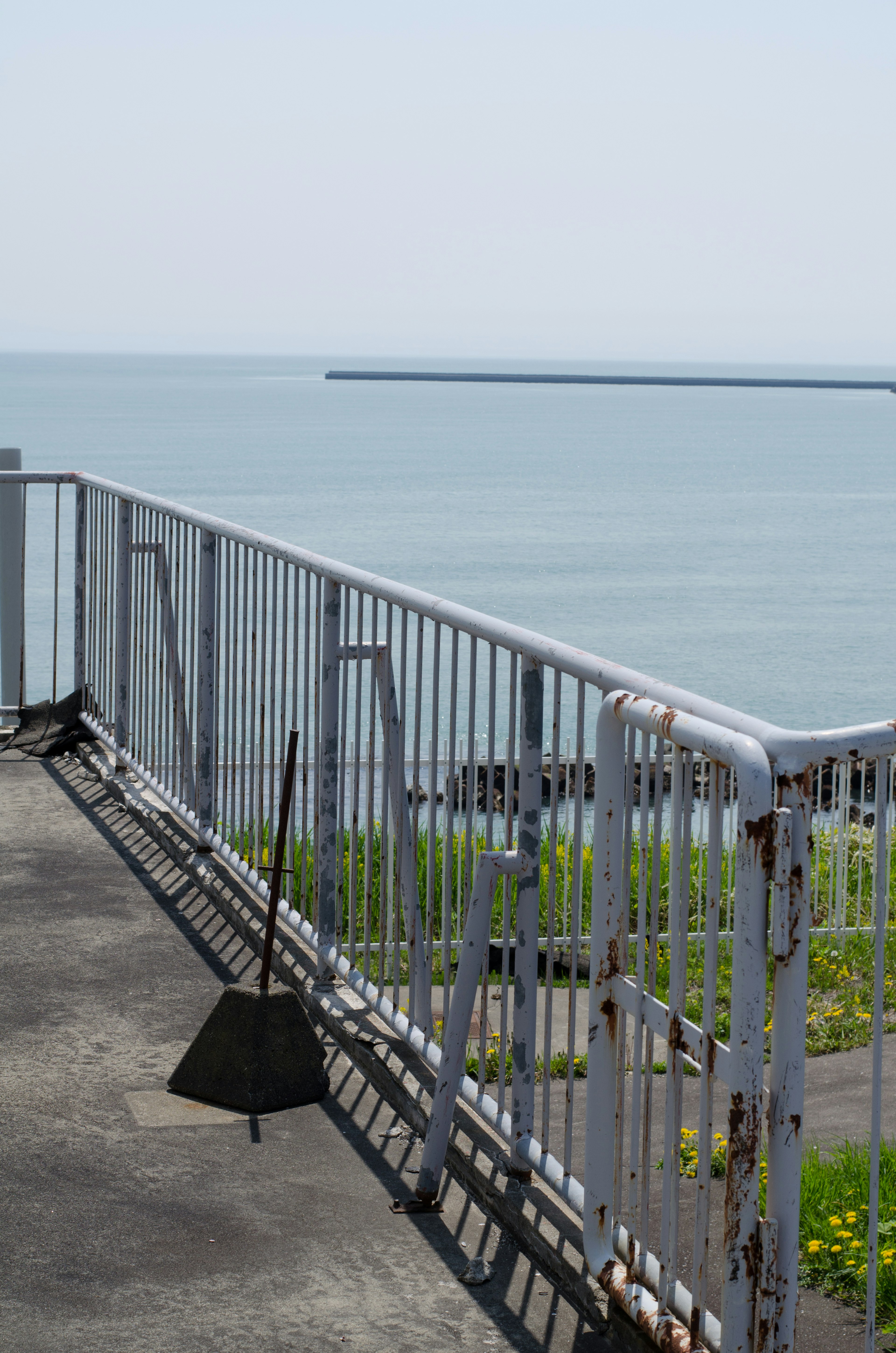 Blick auf das Meer mit einem Geländer und einem schwarzen Objekt