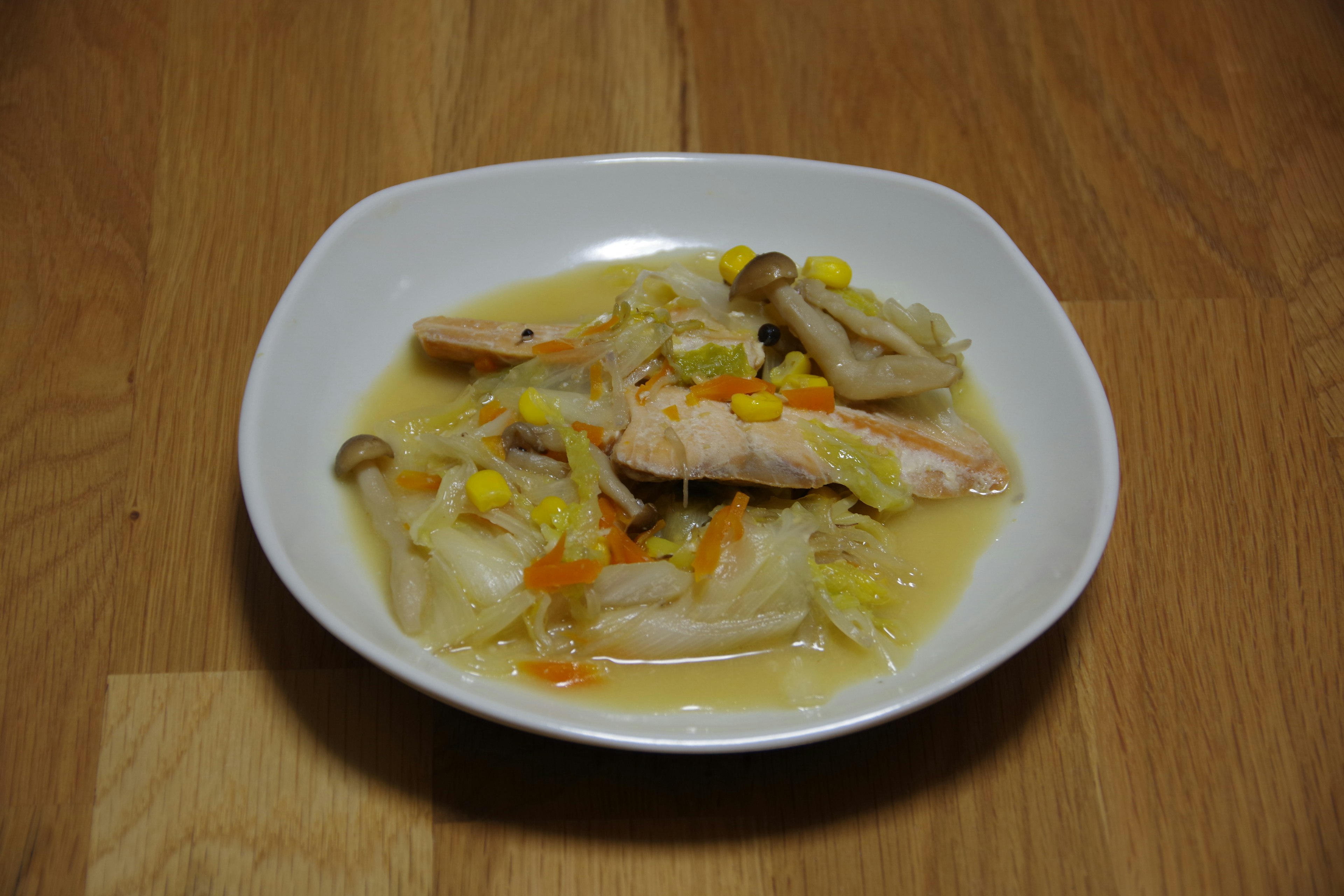 A dish of chicken and vegetables in broth served in a white bowl