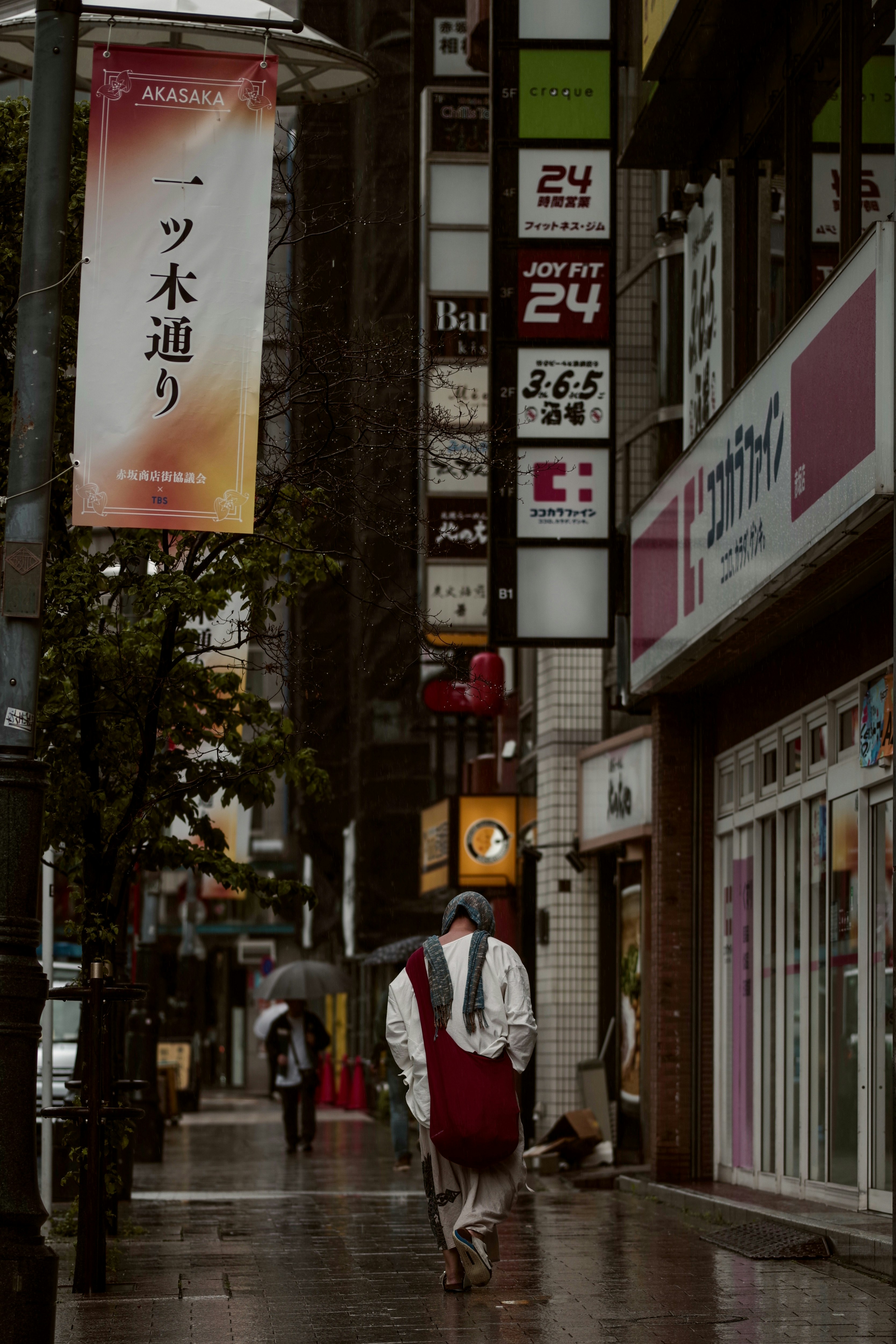 비 오는 도시 거리와 다양한 상점 간판이 있는 모습