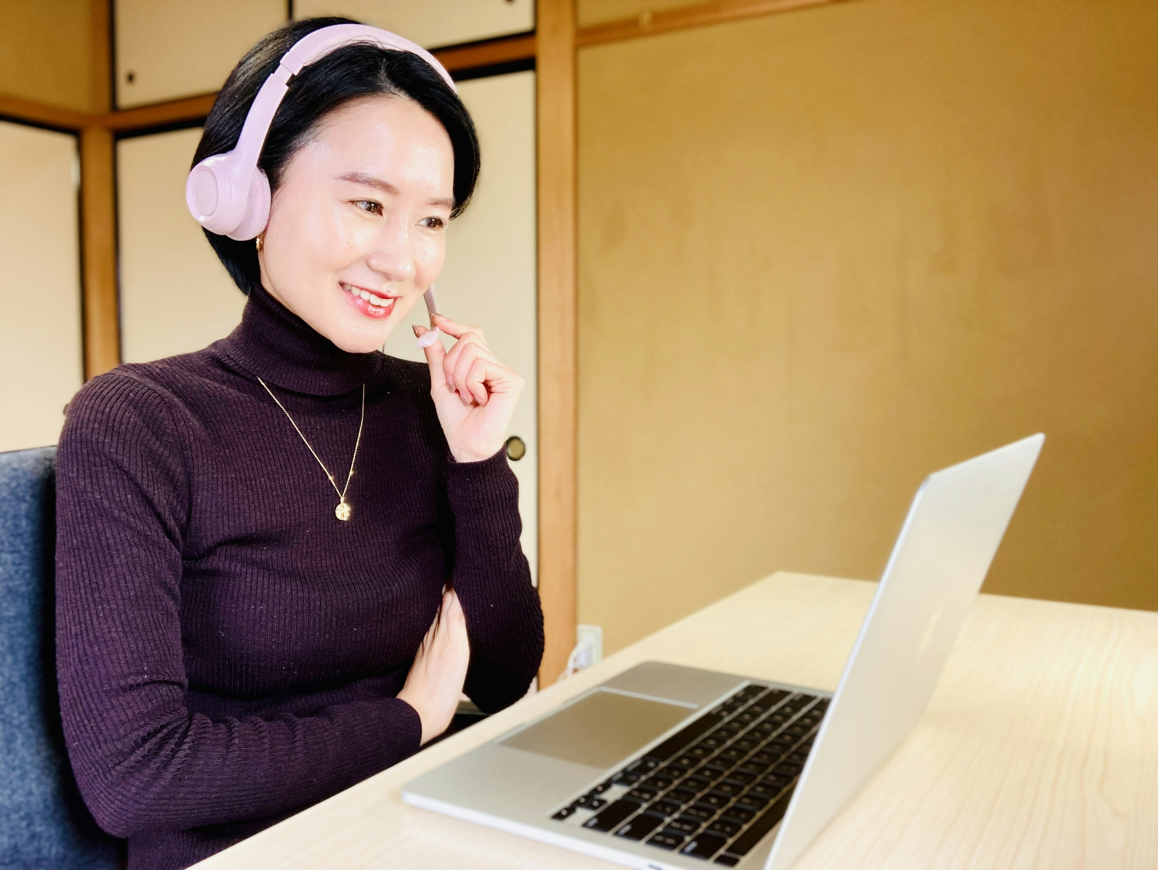 Jeune femme portant des écouteurs souriant à un ordinateur portable