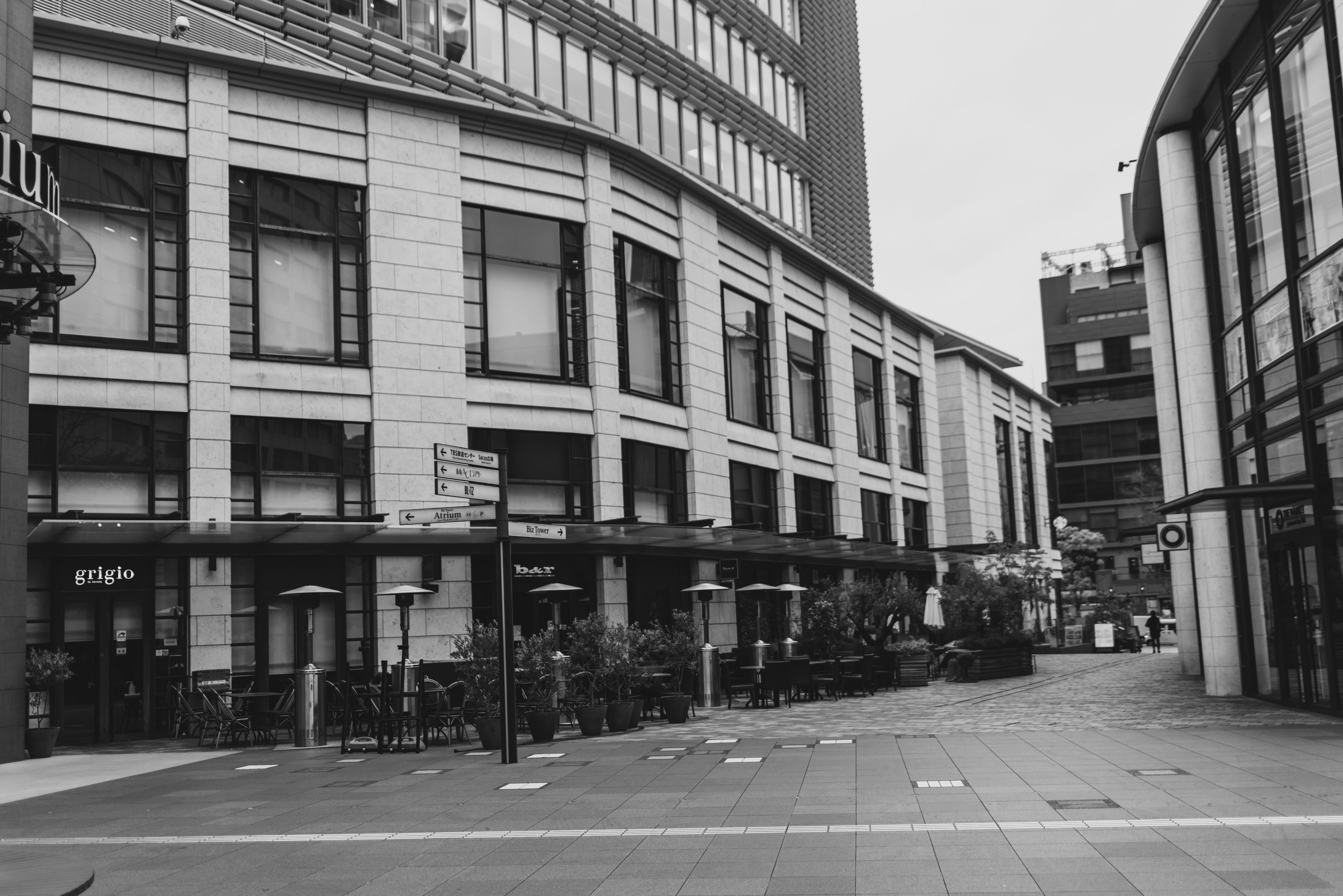 Imagen en blanco y negro de un paisaje urbano con una terraza de café y edificios modernos