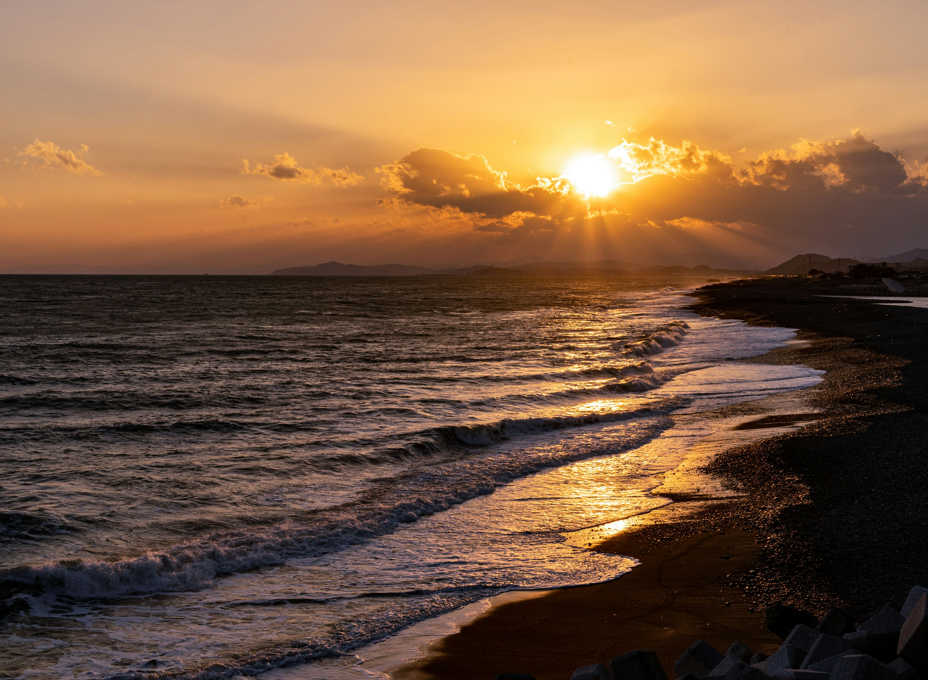 夕日が海に沈む美しい風景波が浜辺に寄せている