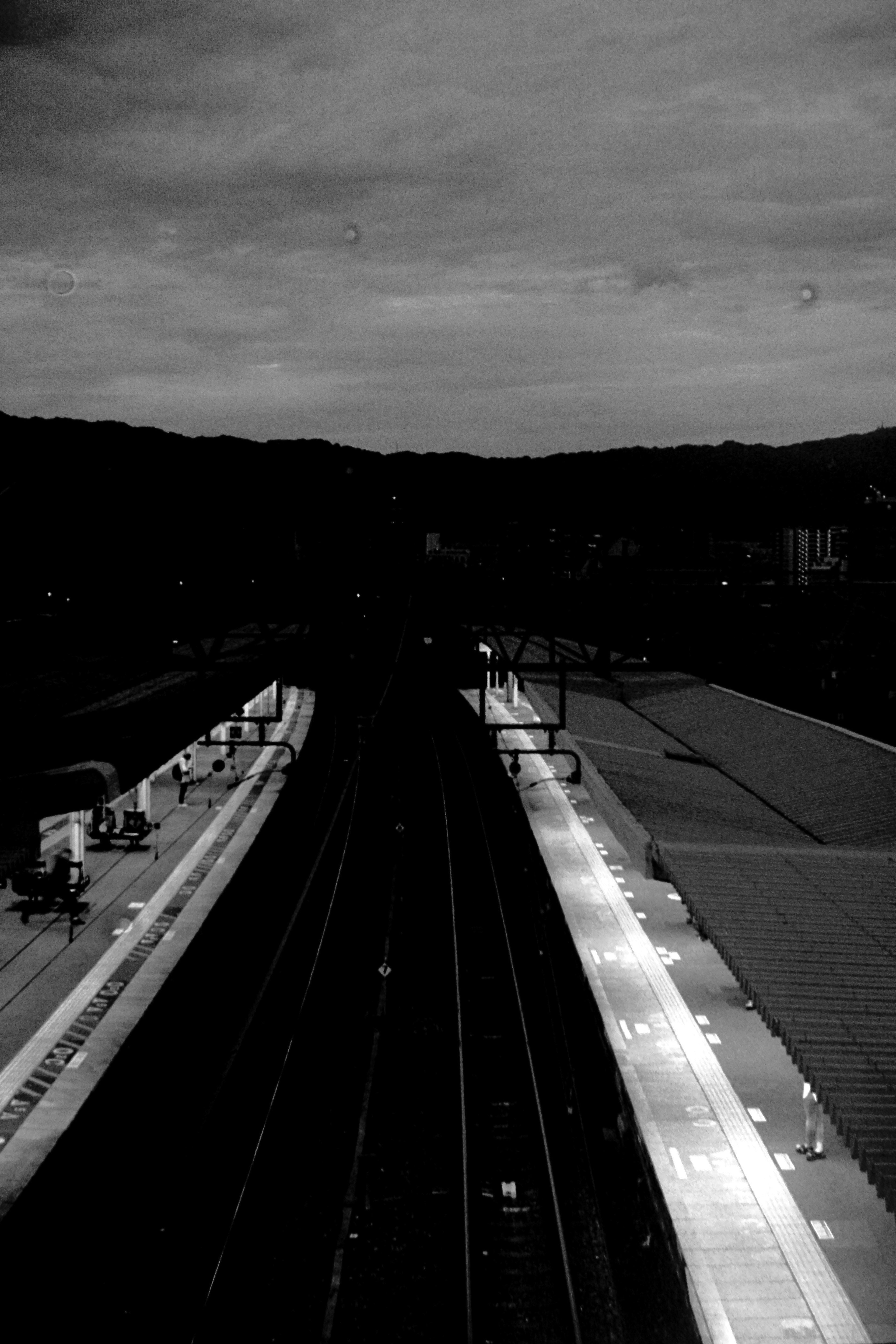 Scena di stazione ferroviaria scura con binari e banchine