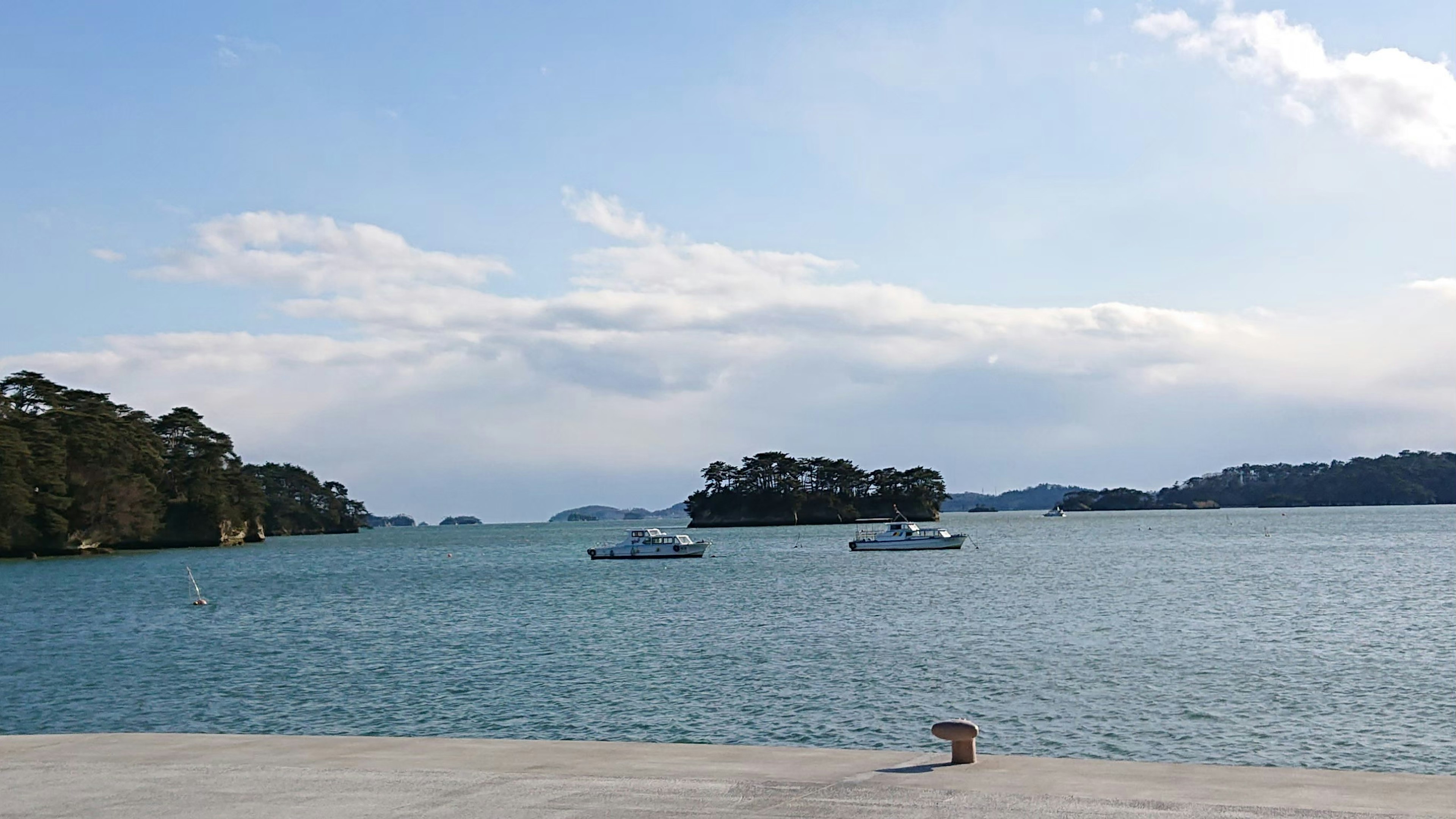 青い海と空が広がる風景に小さな島とボートが見える