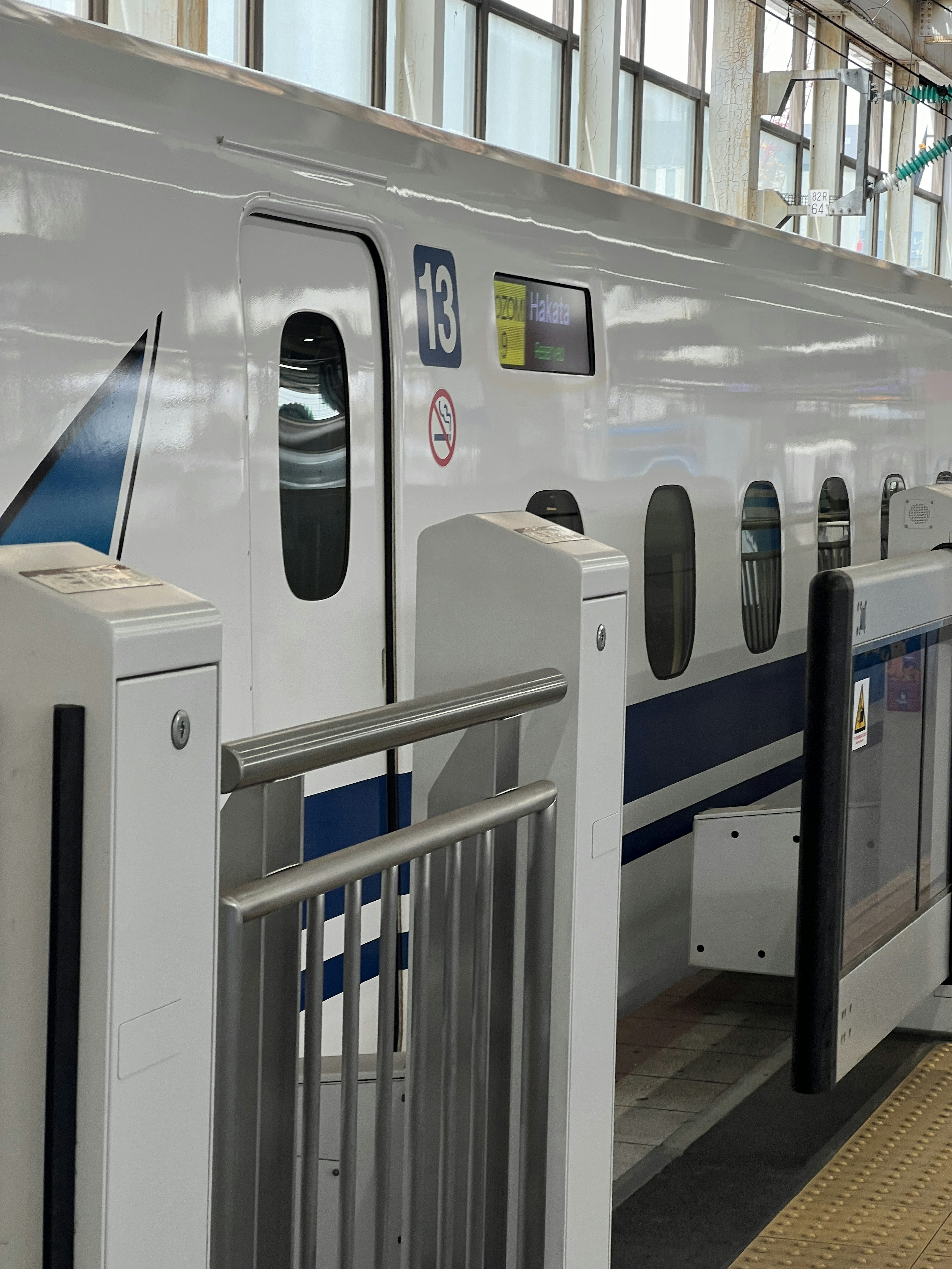 A section of a Shinkansen train at a station with visible windows and doors