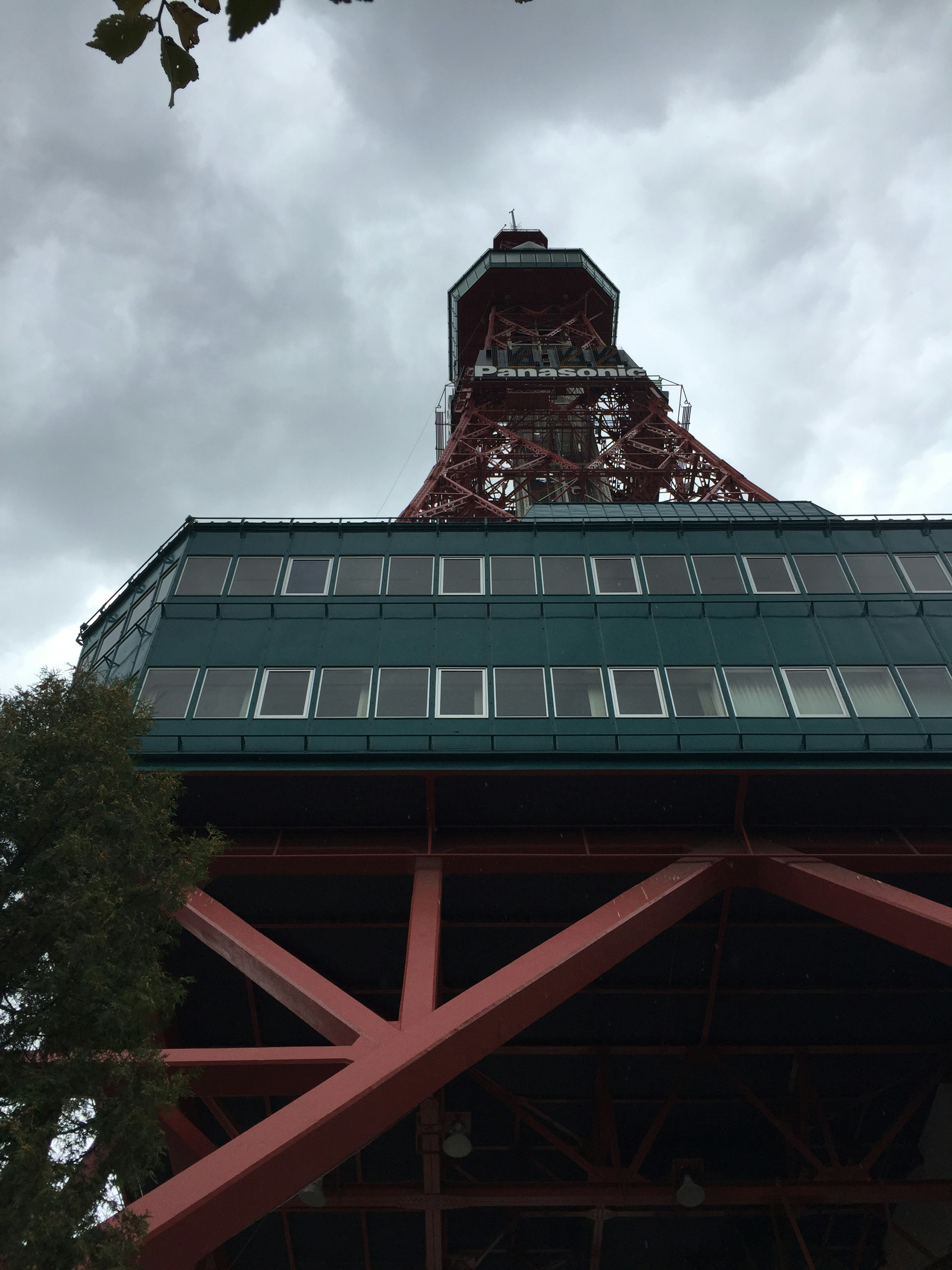 Foto desde abajo mirando hacia arriba a una torre roja con un cielo nublado de fondo