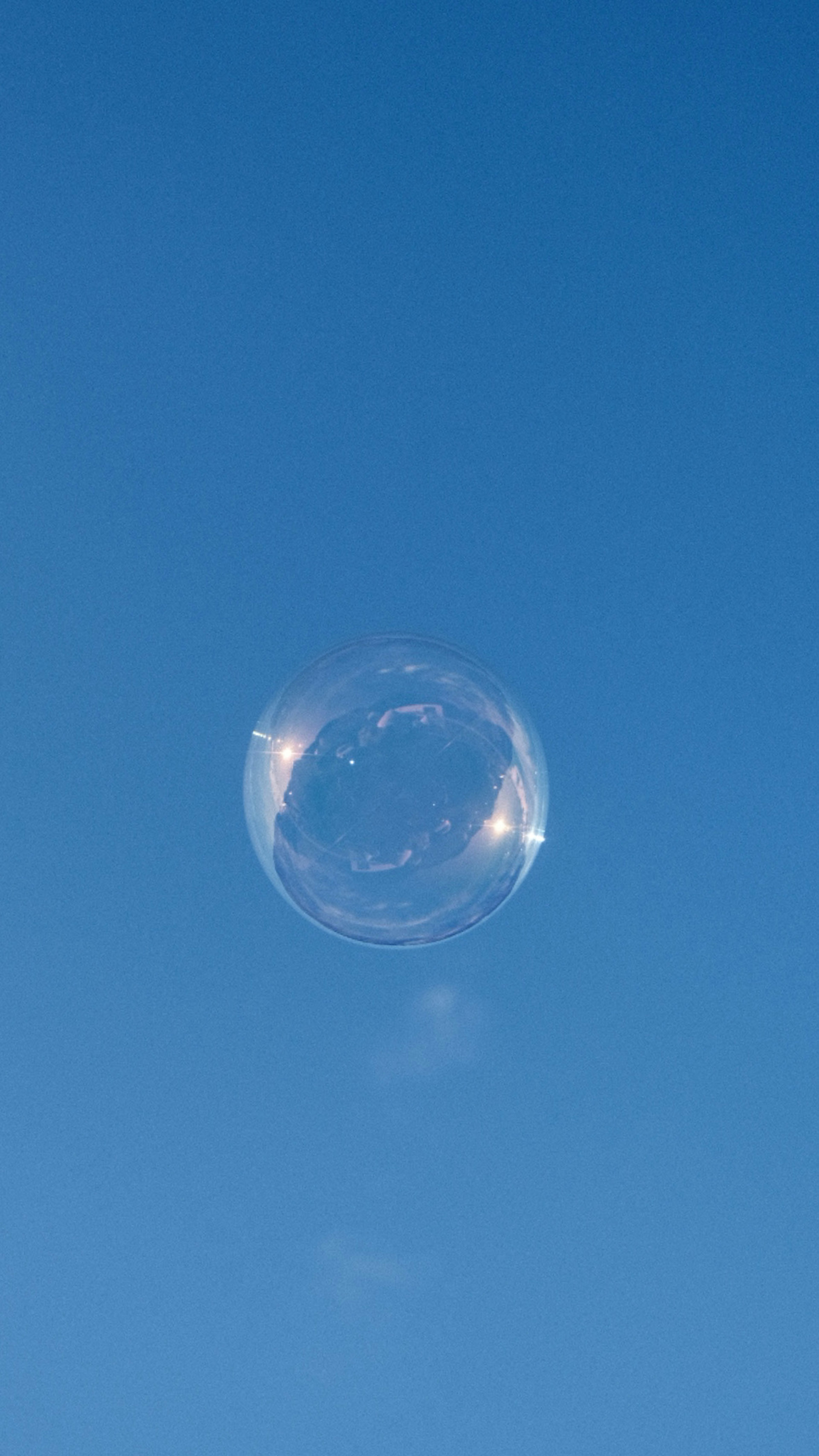 Una burbuja de jabón transparente flotando en un cielo azul