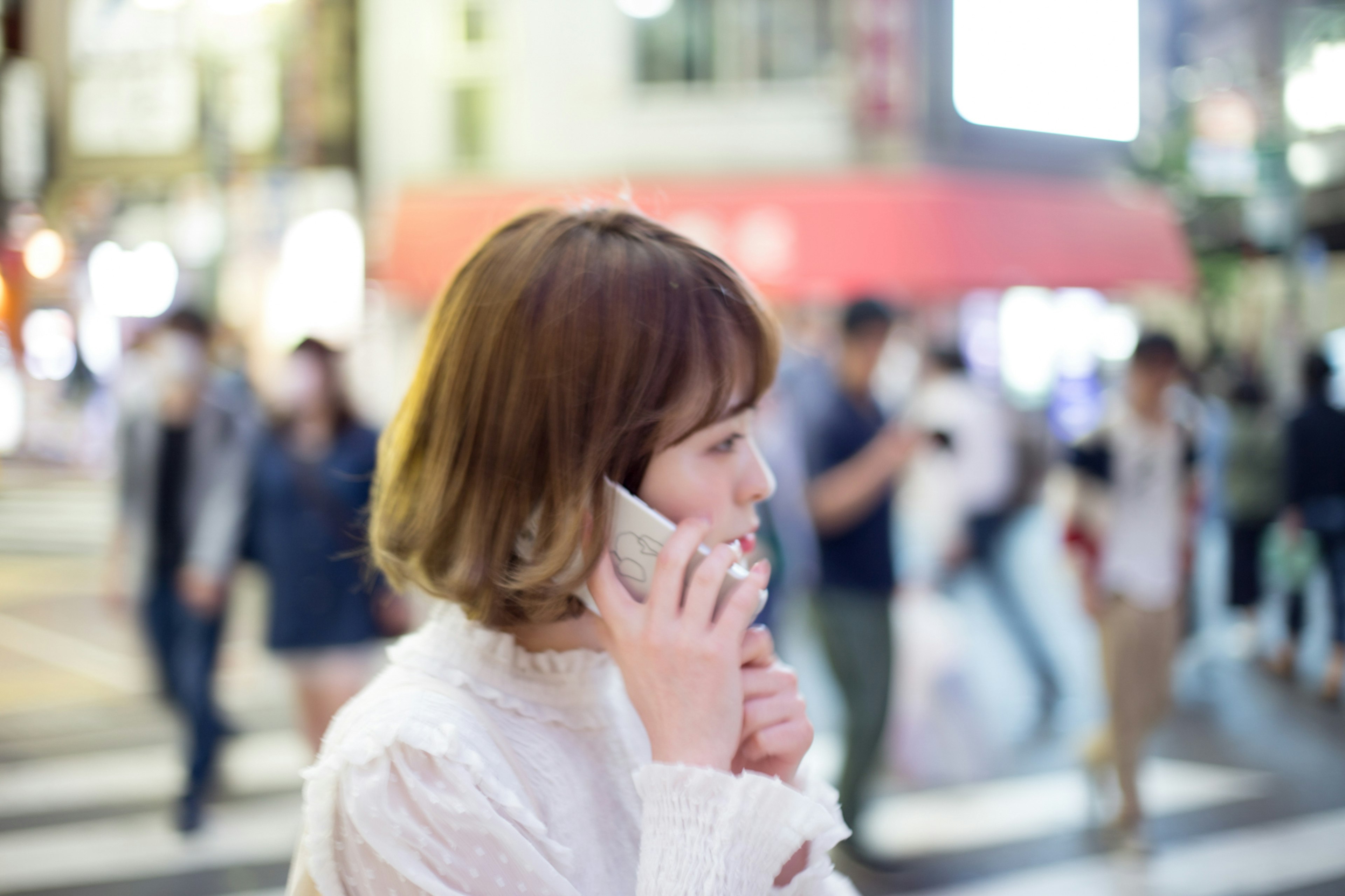 街中で電話をかけている女性の横顔が印象的な夜の風景