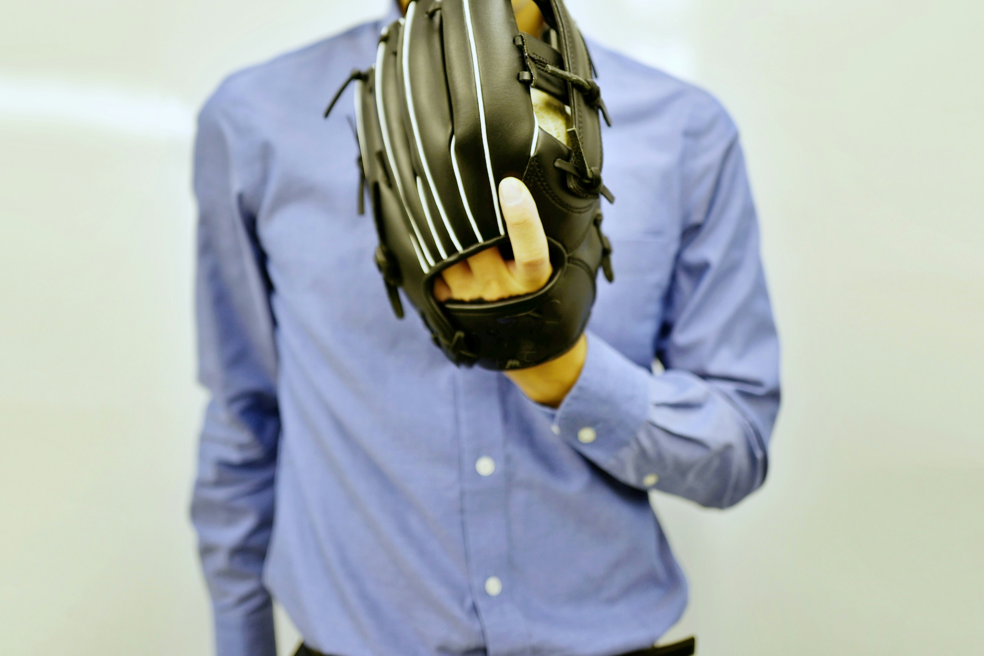 Person in a blue shirt holding a baseball glove with fingers extended