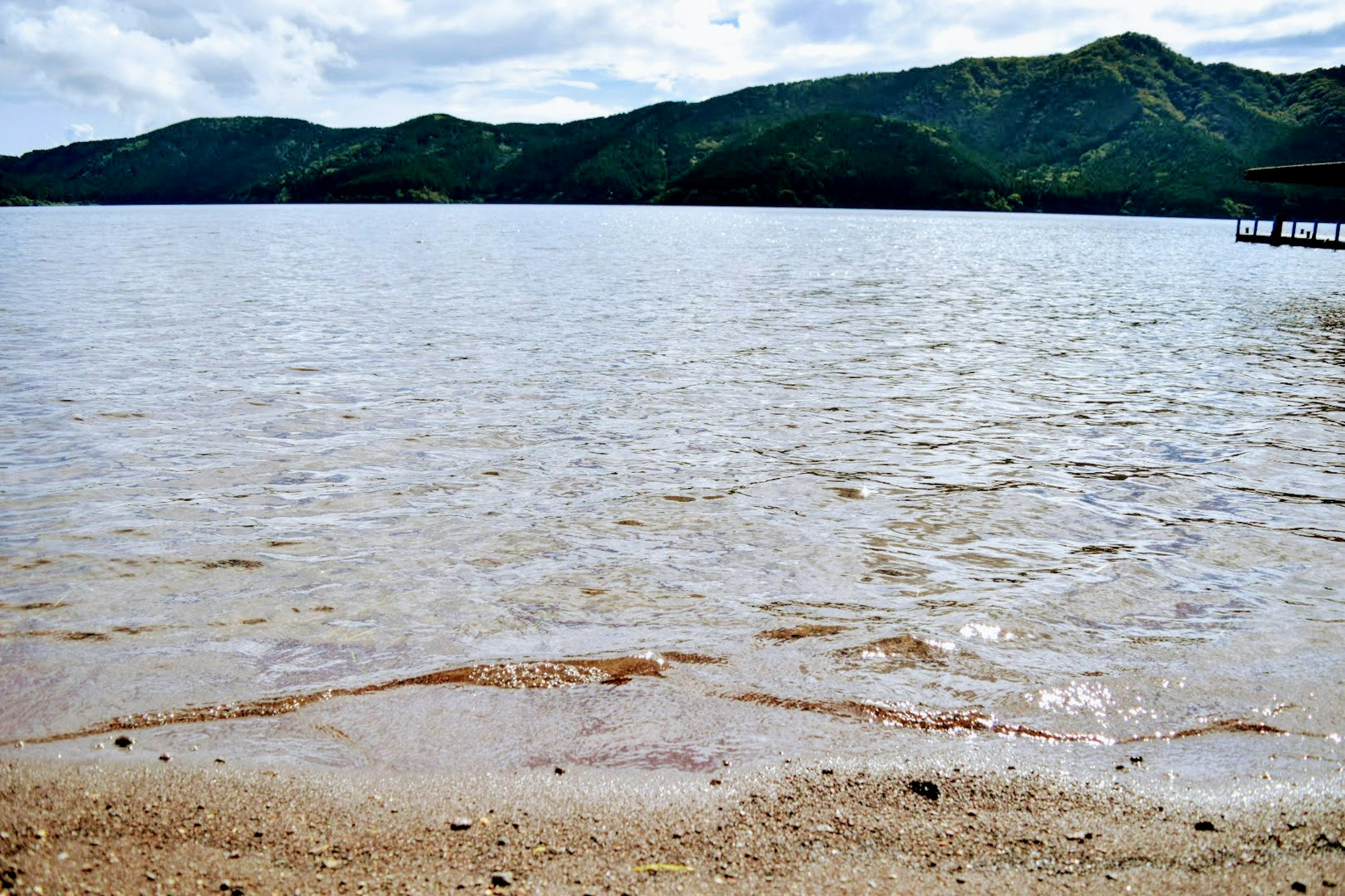 Superficie calma del lago con montagne verdi sullo sfondo