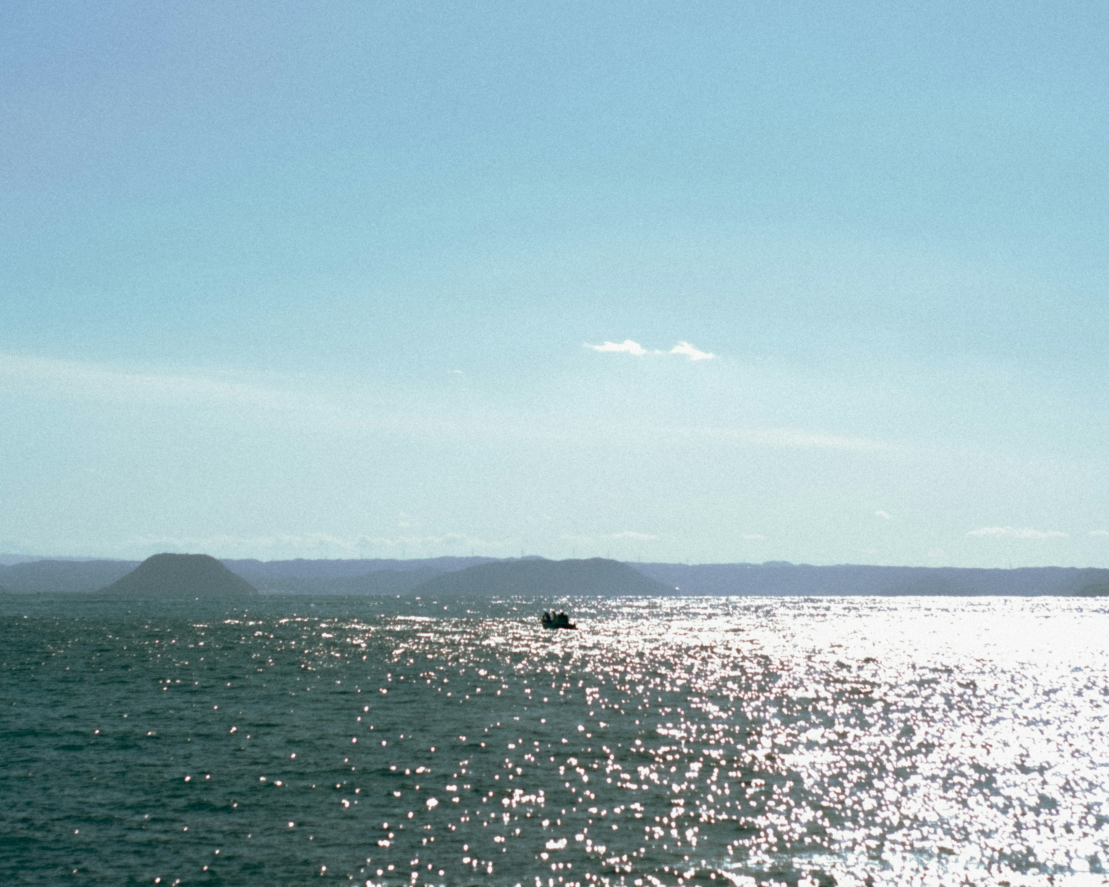 青い海と明るい空に浮かぶ小舟の景色