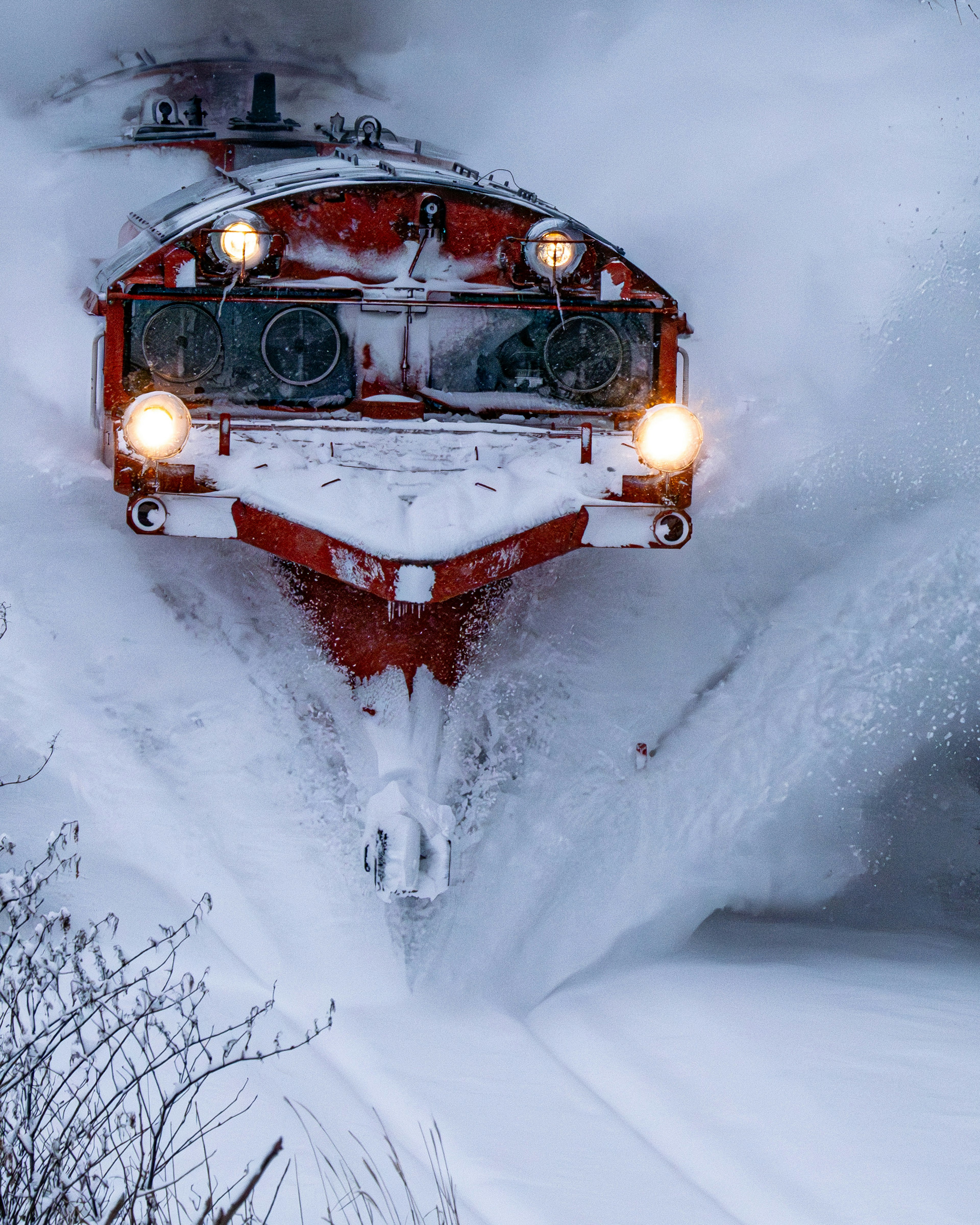 Train de déneigement rouge coupant à travers la neige profonde