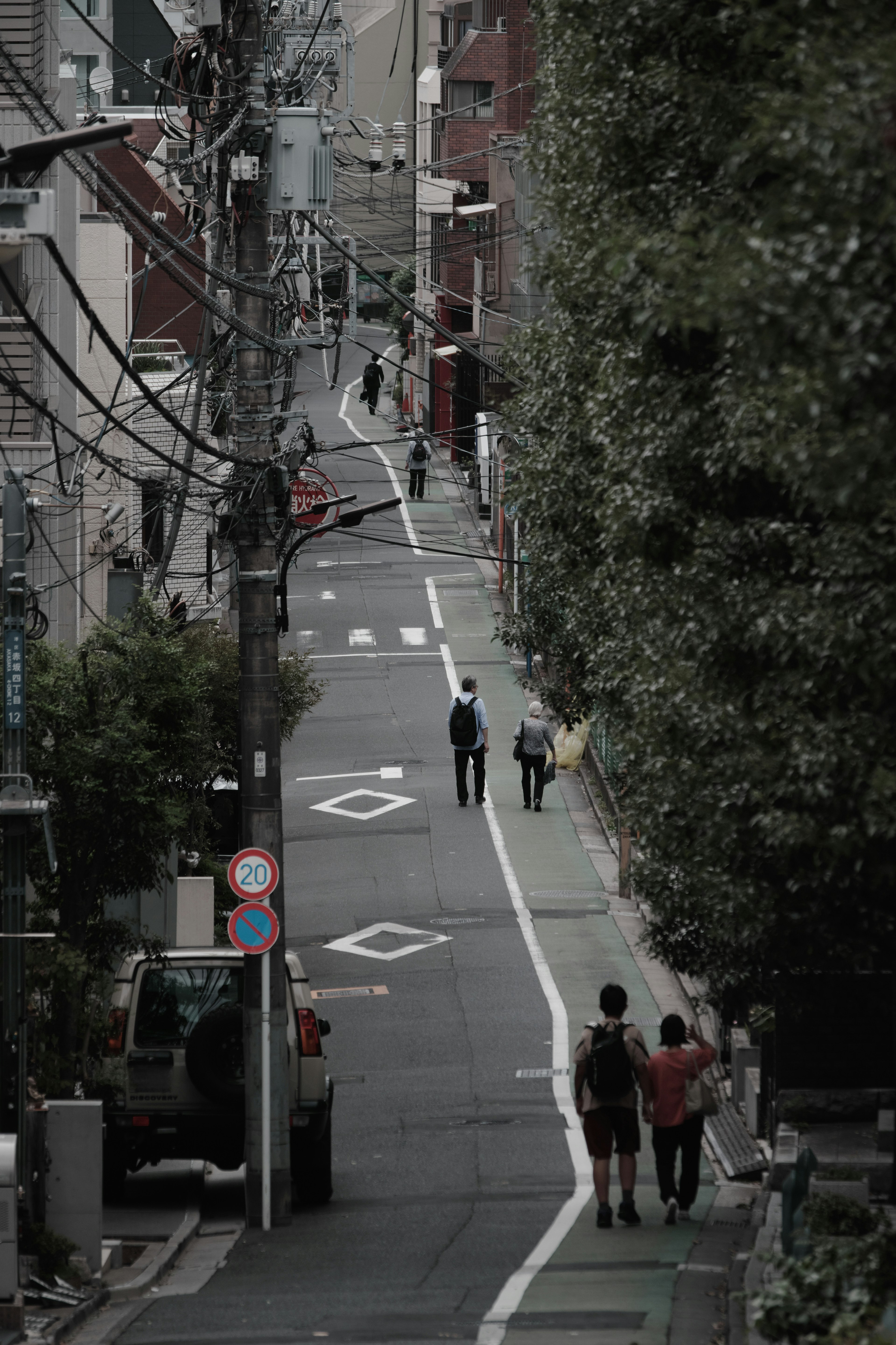 Calle estrecha con peatones y líneas eléctricas