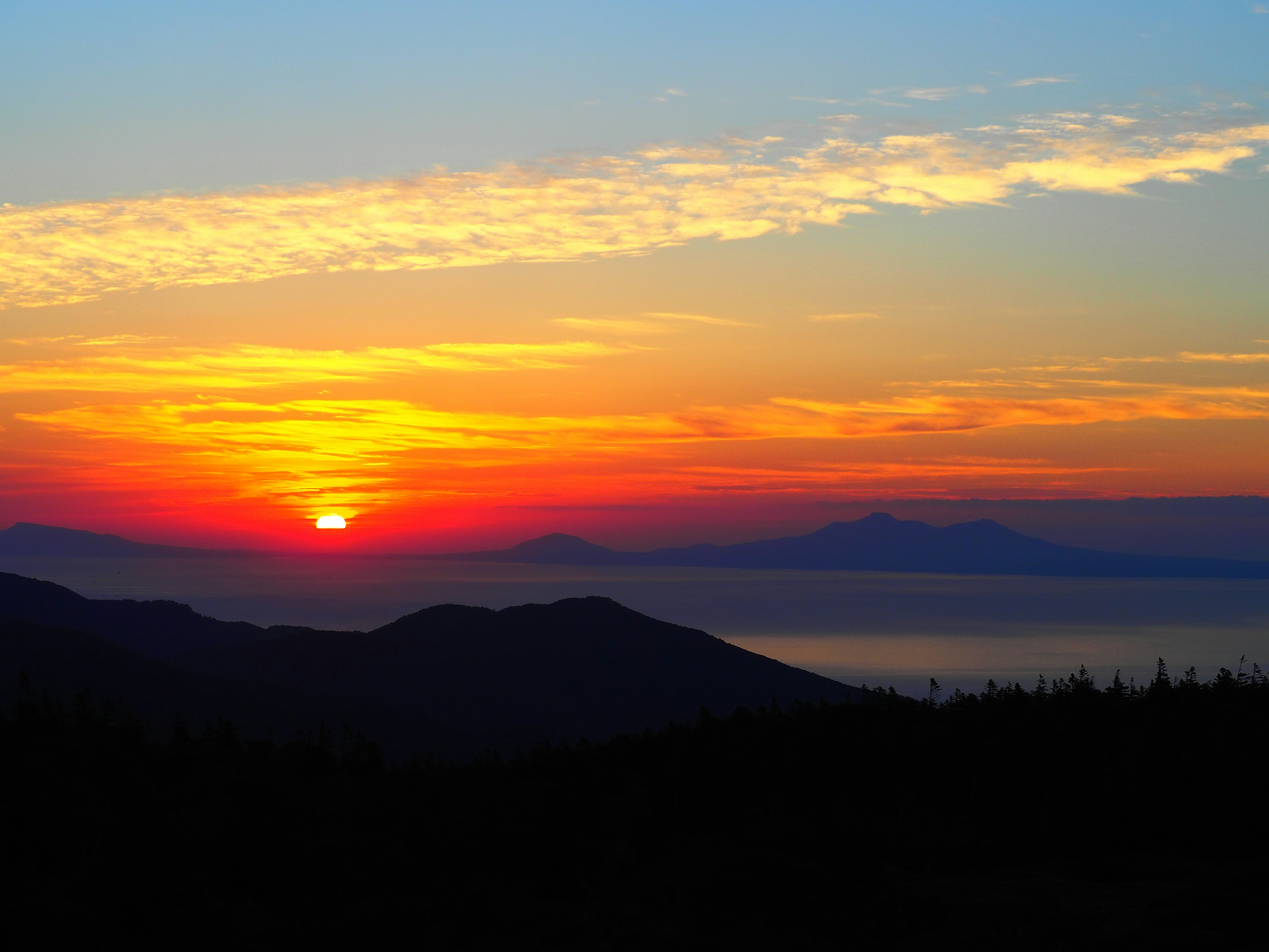 Stunning sunset landscape with mountains and sea silhouettes