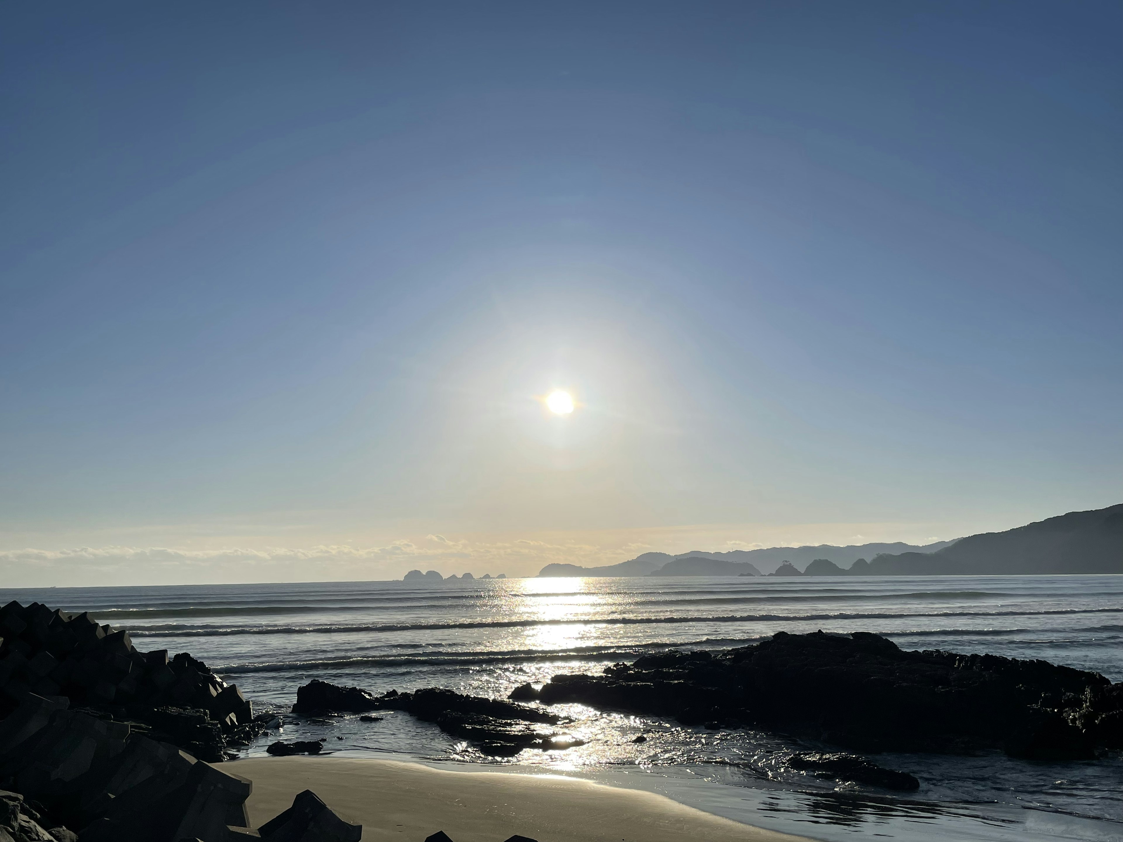 Ruhige Strandansicht mit Sonnenuntergang, der sich im Wasser spiegelt