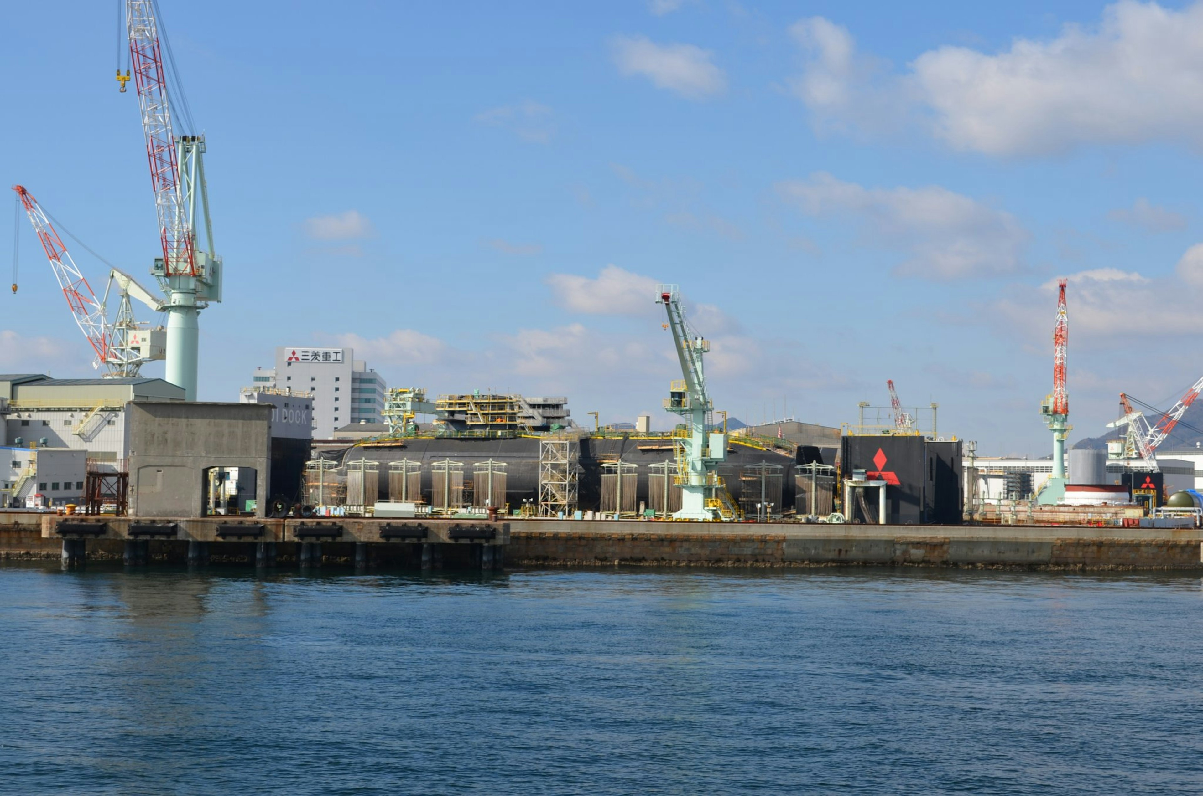 Harbor scene featuring cranes and industrial buildings with a blue sky